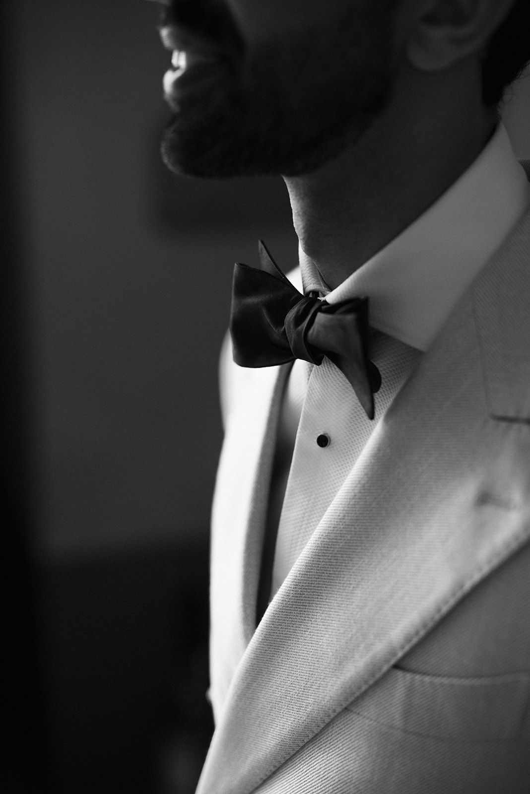 Close-up black and white photo of formal white tuxedo with black bow tie and crisp dress shirt details.