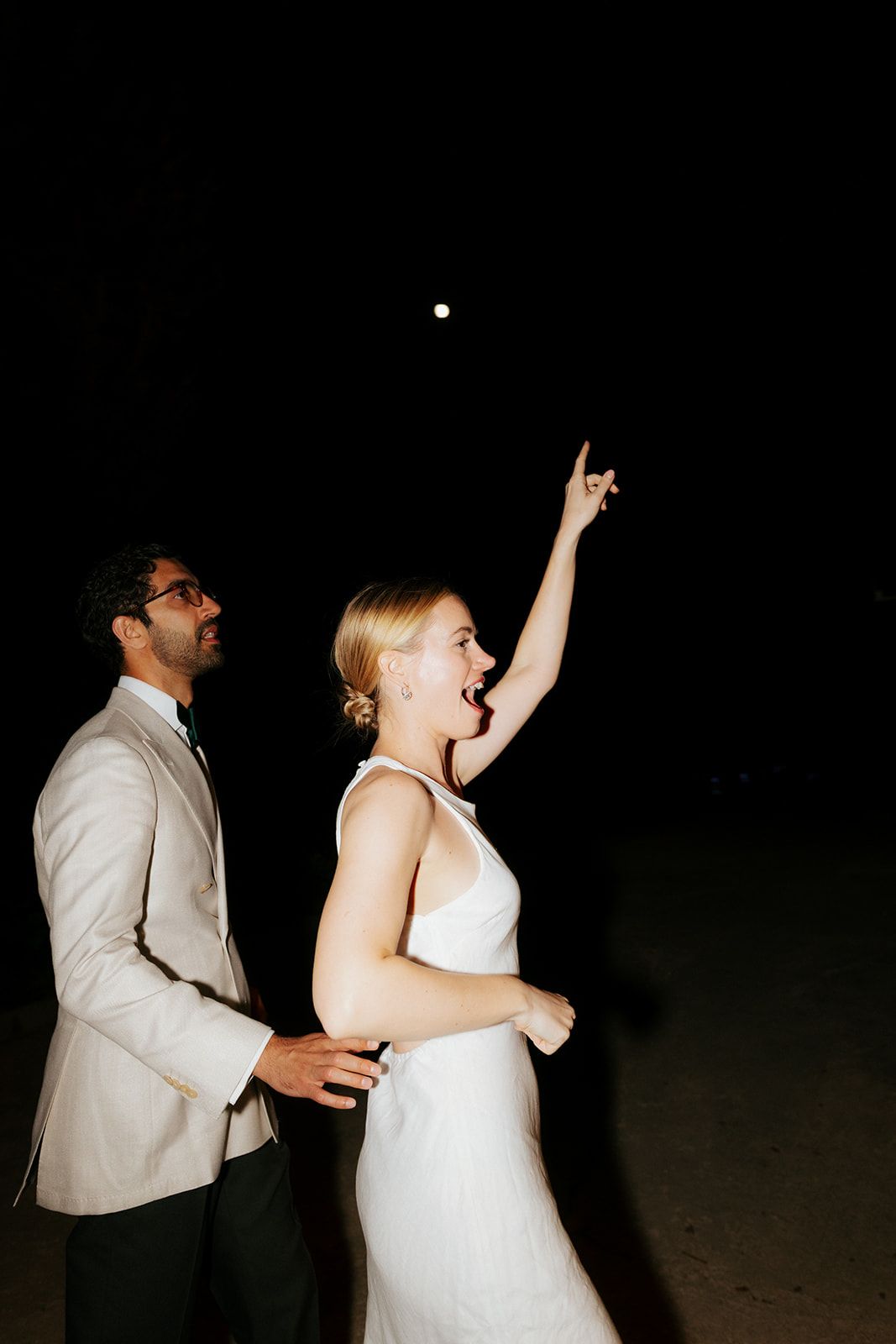 Wedding couple dances energetically on a dark dance floor in sequence showing joyful celebration movements.