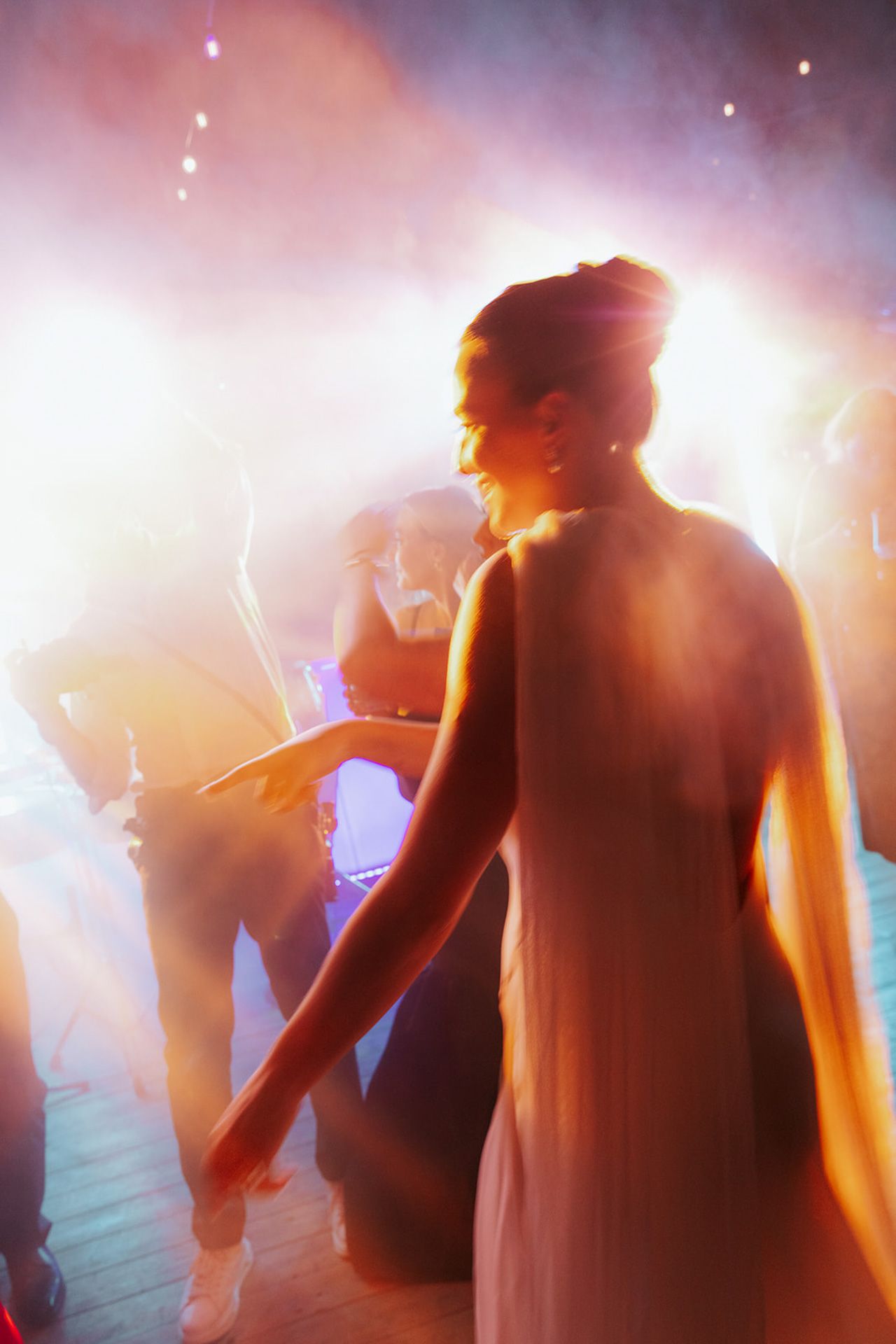Silhouetted figure in a dreamy atmosphere with bright backlighting and hazy smoke effects at a dance party.