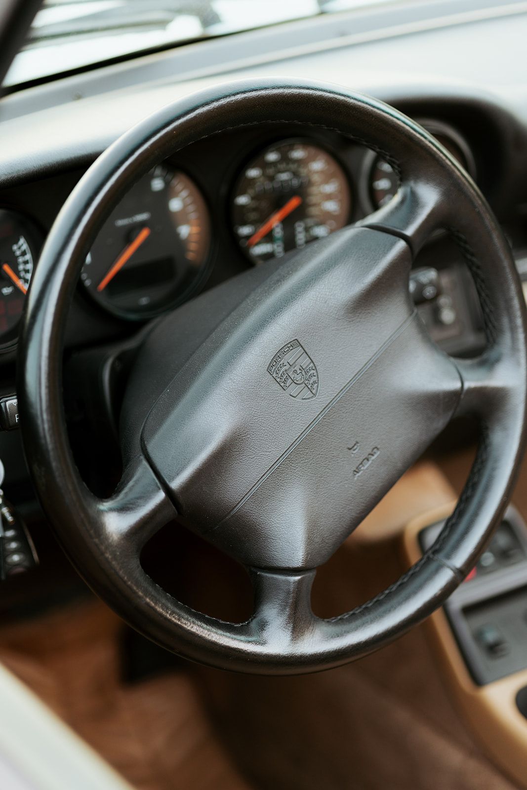 Close-up sequence of a Porsche steering wheel and dashboard gauges showing different angles and lighting conditions.