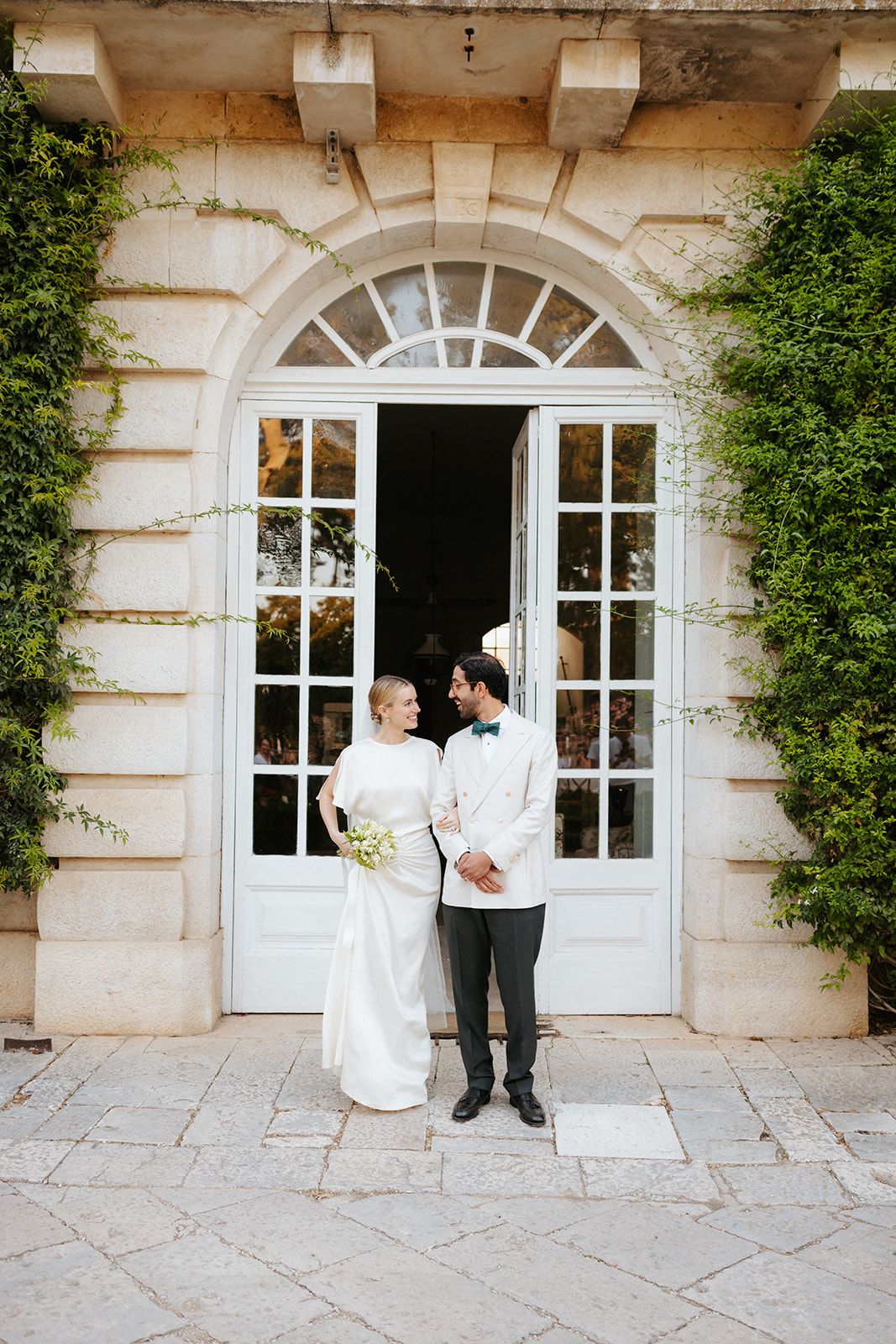 Elegant arched doorway entrance of a classic stone building with climbing vines framing a romantic wedding scene.