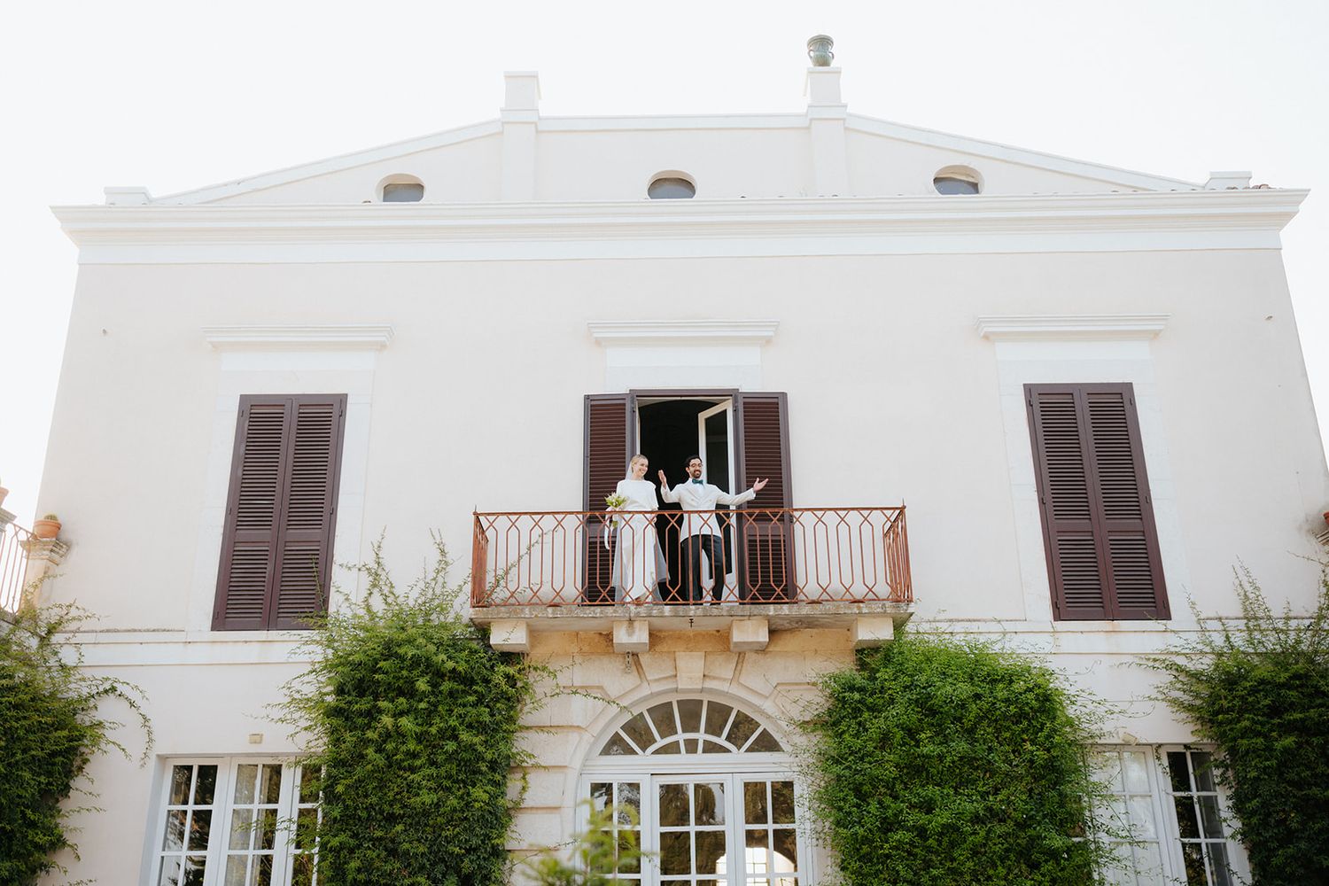White Mediterranean style villa with brown shutters and ornate balconies photographed from different exterior angles.