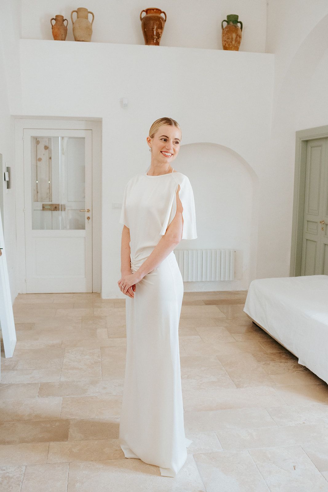 White dress display sequence across minimalist white interior space with terracotta pots on shelf.