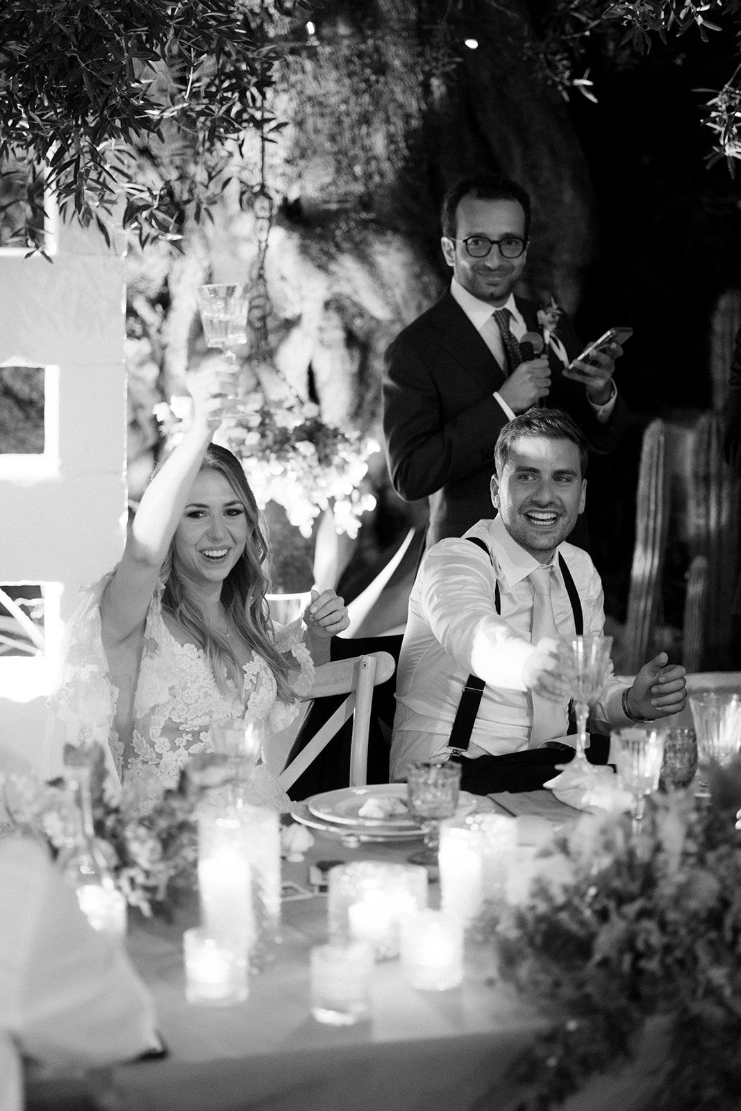 Wedding guests enjoying an intimate candlelit reception dinner with greenery decorations overhead.