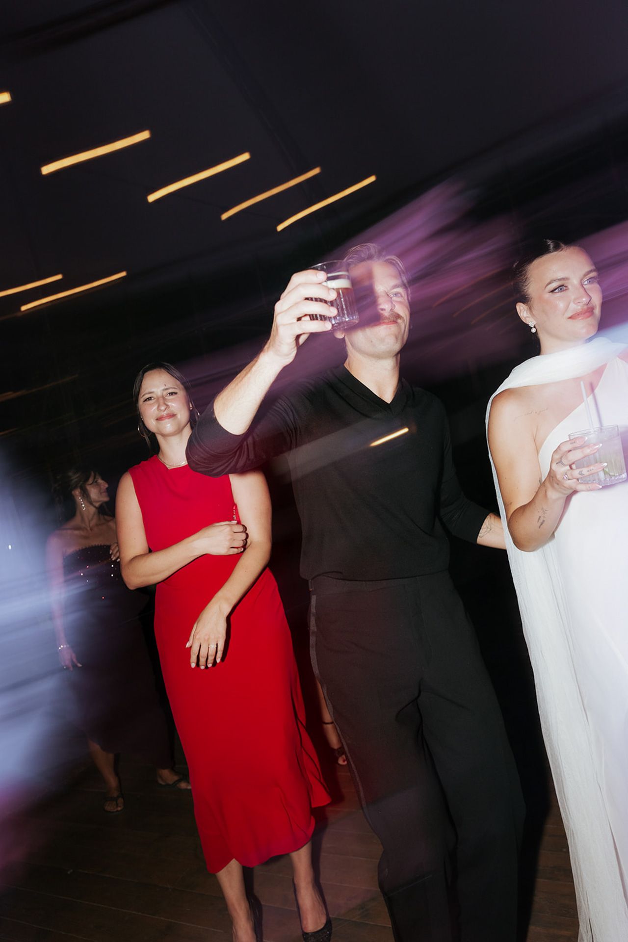 Motion-blurred dance floor photos show people in red and white outfits moving at a party under dim lighting.