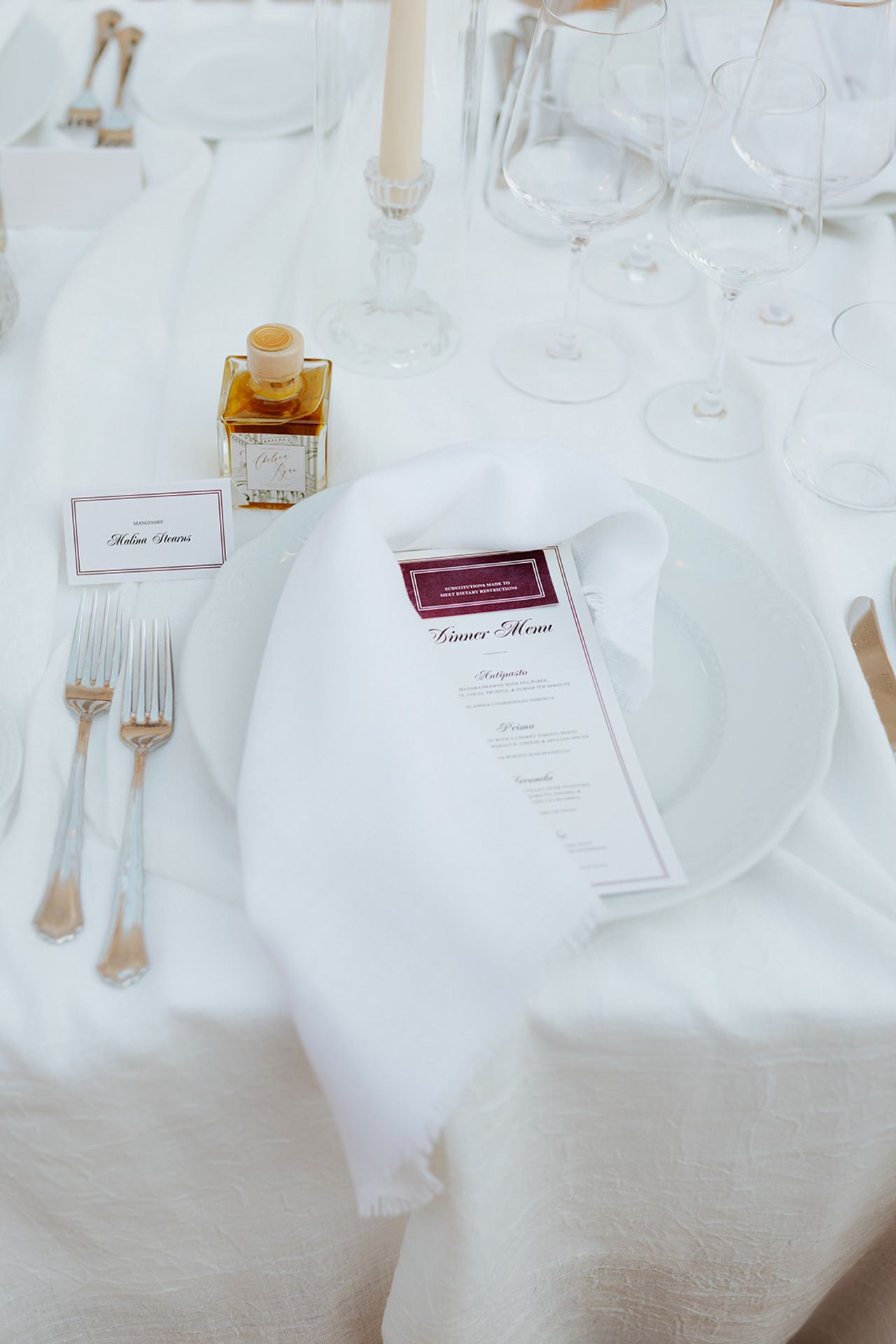 Elegant white table setting with place cards and silverware on crisp linens at a formal dining event.