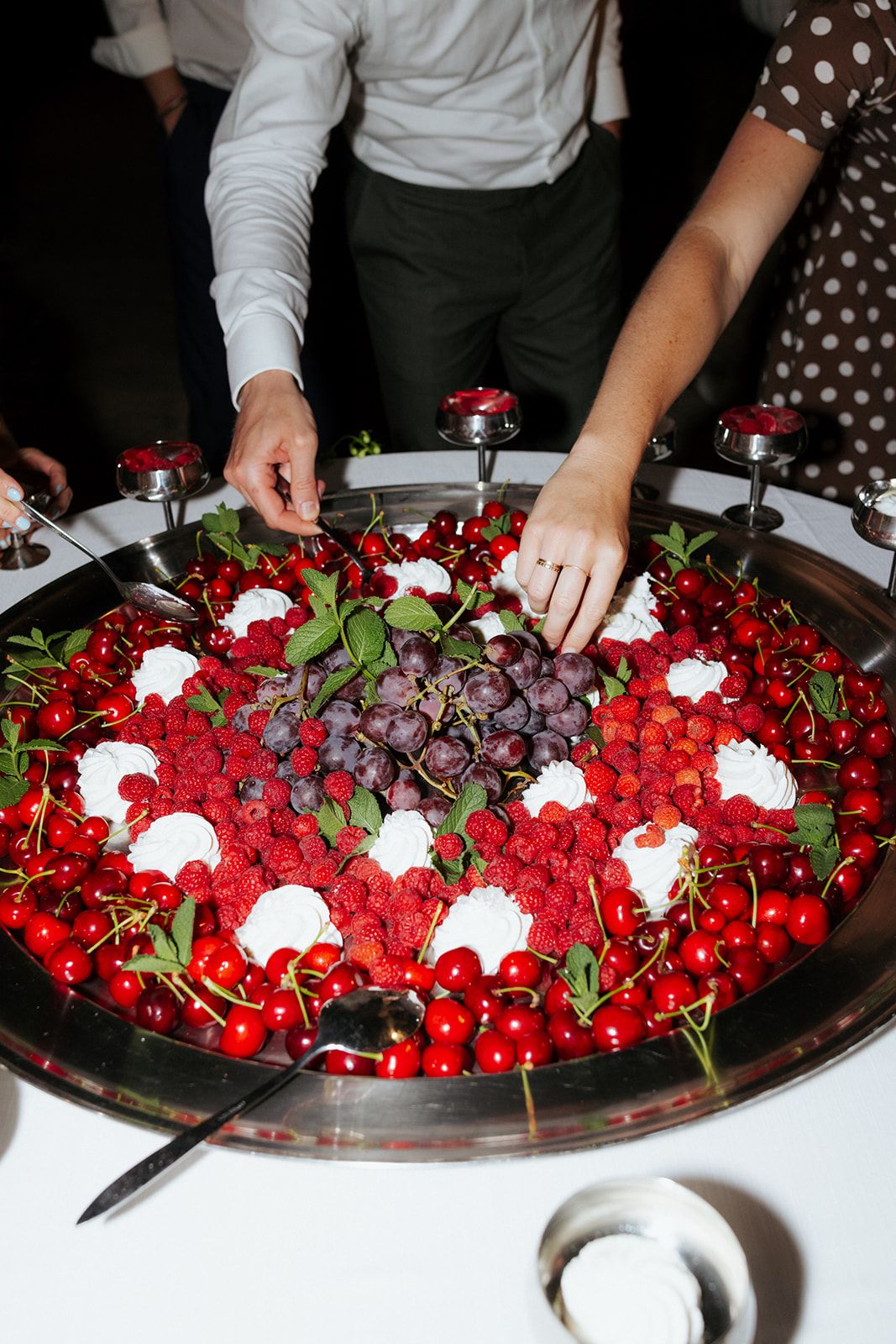 A beautiful platter of fresh red cherries arranged with white flowers and greenery on an elegant serving tray.