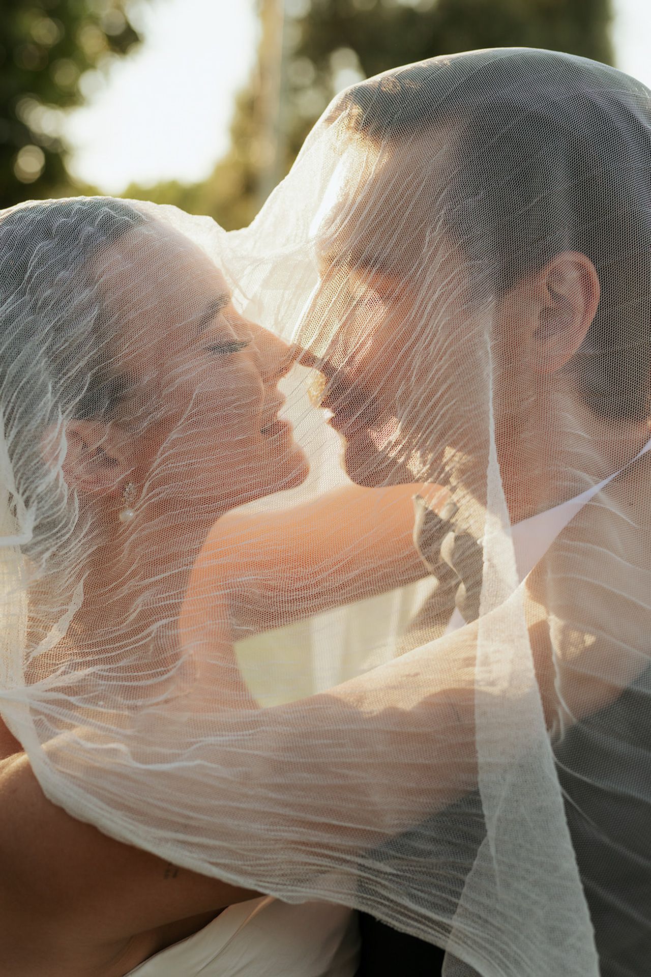 A romantic sequence of wedding photos showing a couple kissing under a flowing veil at sunset.