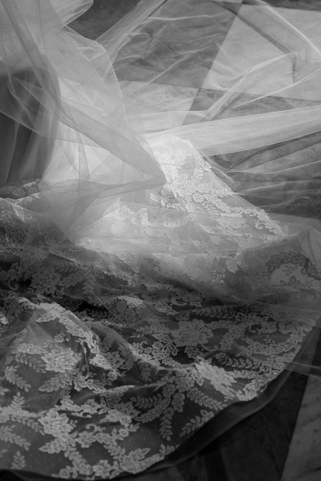 Close-up view of delicate wedding veil layers with intricate vintage lace detailing and ethereal tulle textures.
