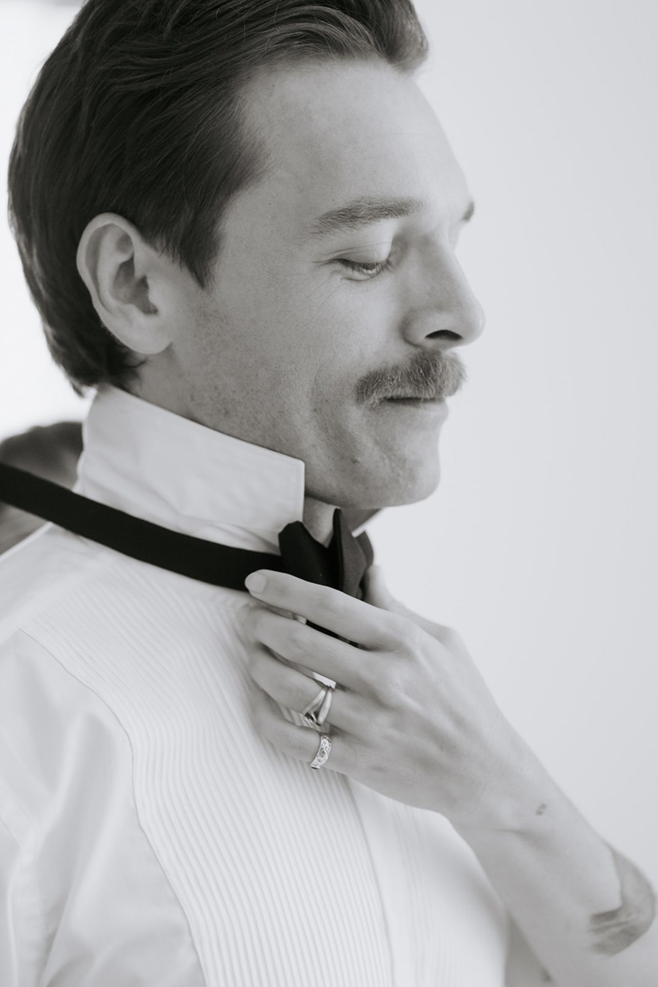 Black and white portrait series showing a person in white adjusting their collar and tie.