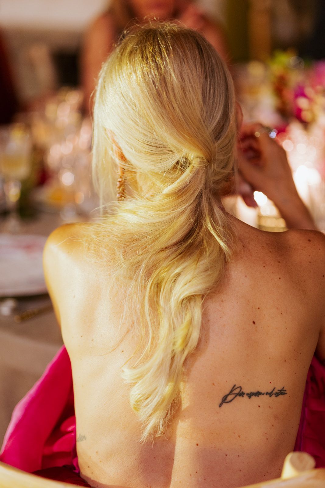 Person's upper back showing a handwritten tattoo against a background with soft focus party decorations.