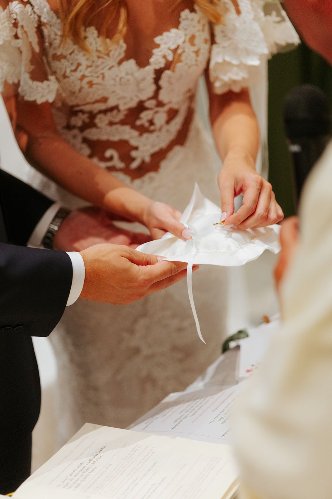 Close-up of hands holding wedding ceremony documents during the signing ritual.