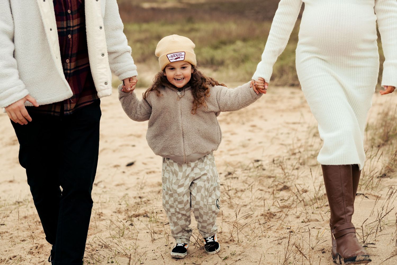 Family walking together on sandy path in winter clothing. Earlhams Beach, Harwich, Essex.