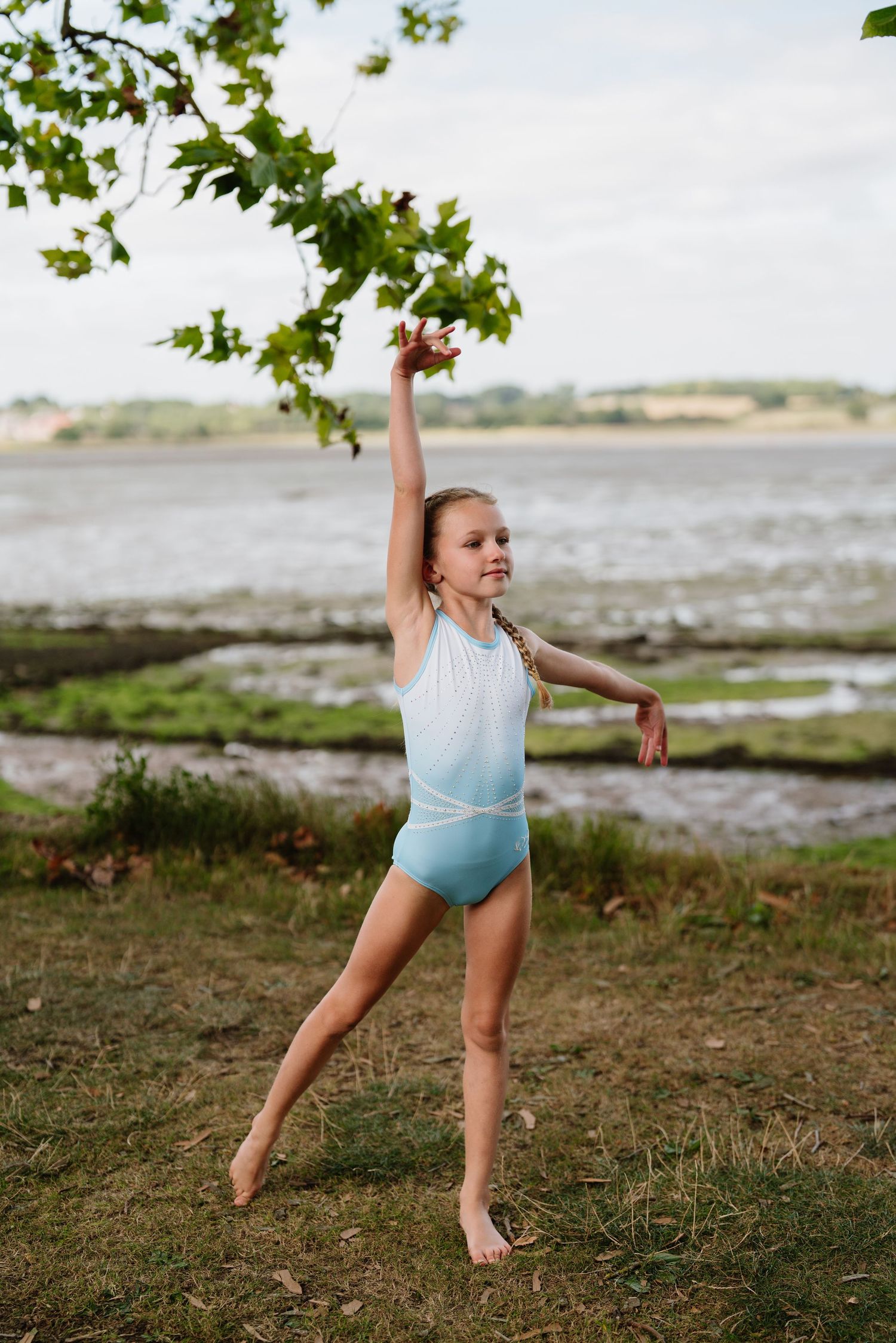 Graceful dance poses demonstrated on grassy terrain near a waterfront. Manningtree, Essex.
