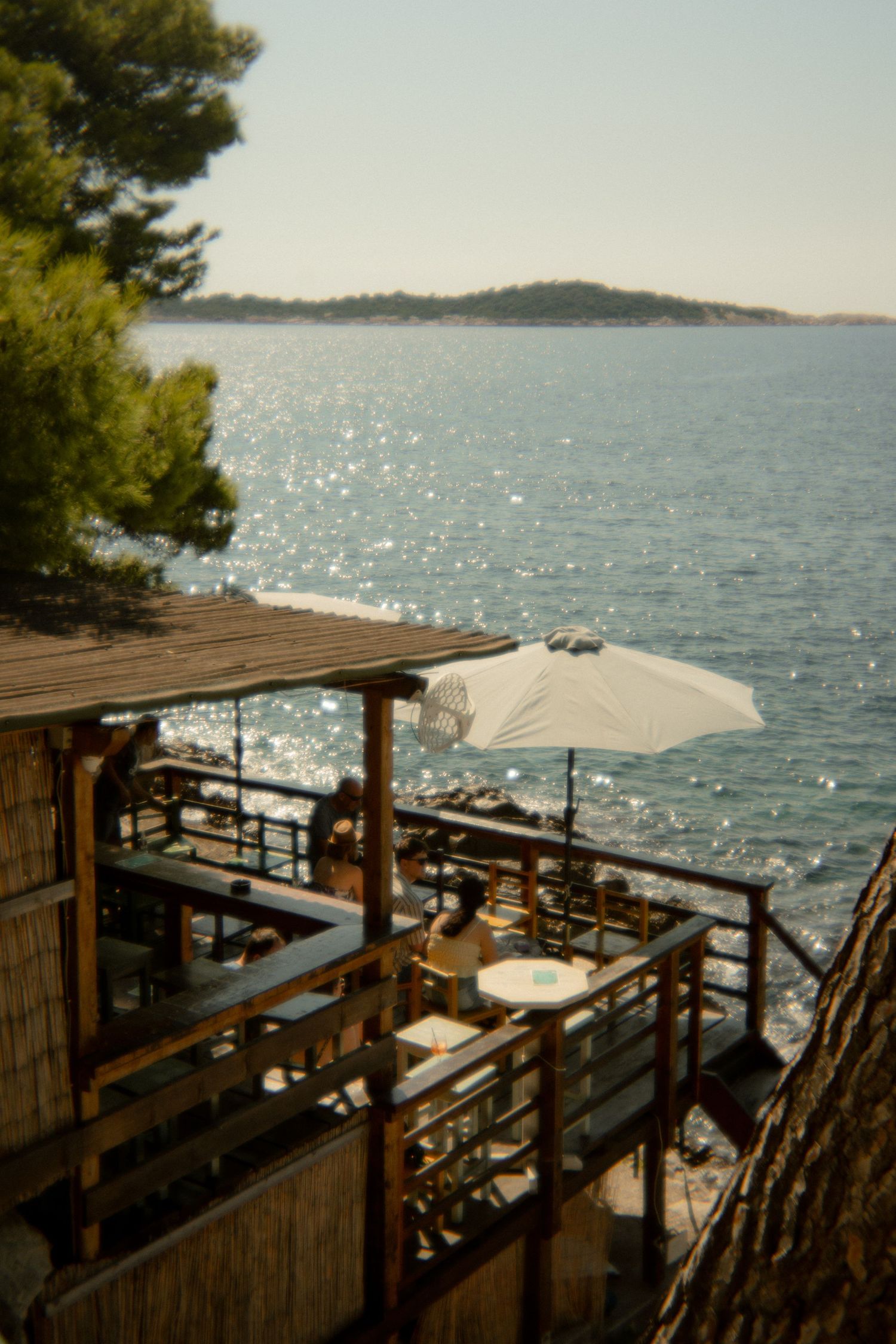 Seaside restaurant terrace with wooden deck overlooking sparkling Mediterranean waters. Croatia.