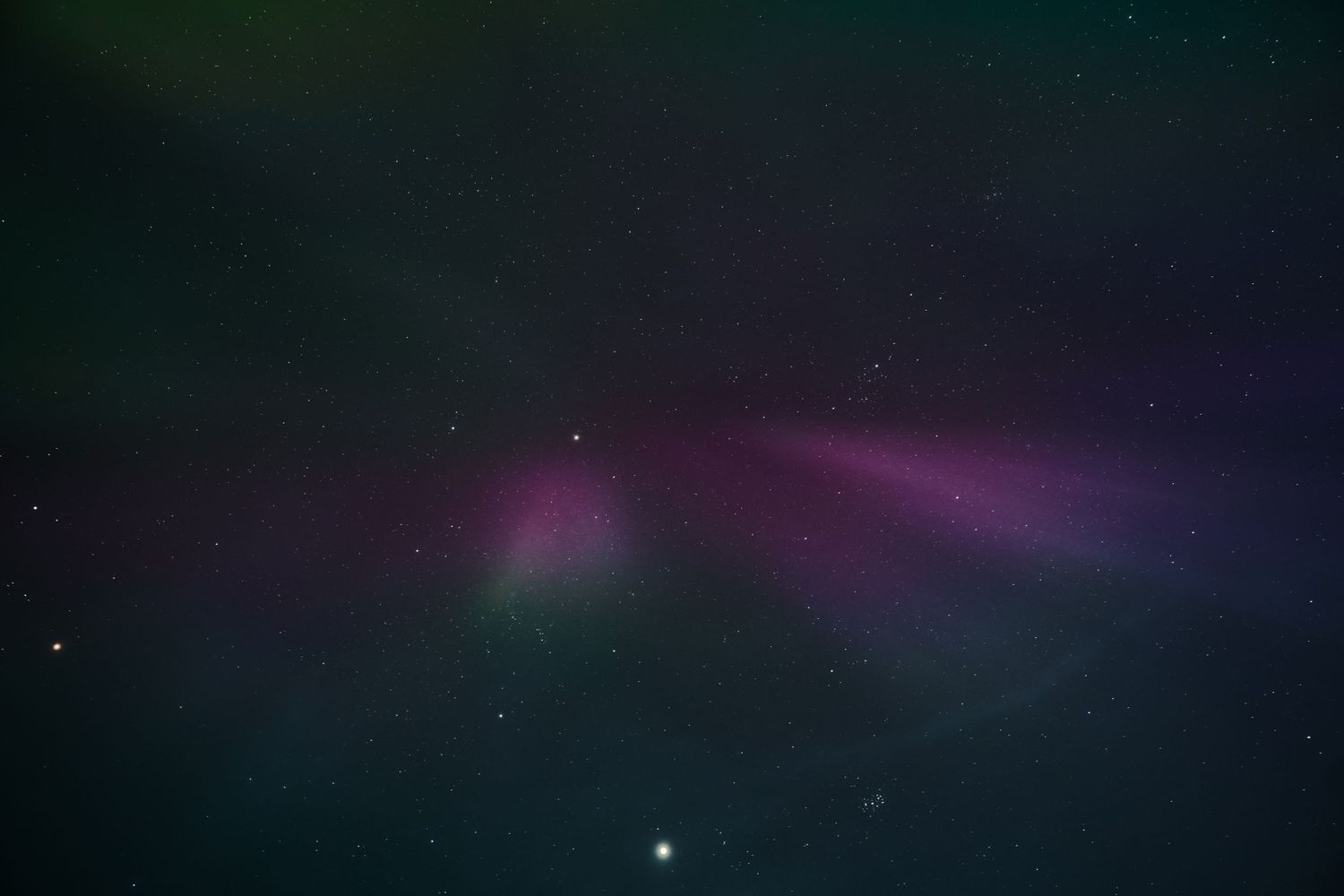 Purple and green aurora borealis illuminates the night sky with stars visible. Iceland.