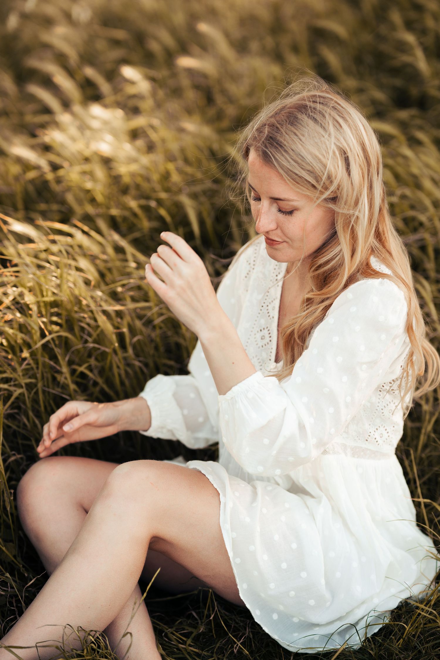 Dreamy portrait series in tall grass wearing a white eyelet dress during golden hour. Manningtree, Essex.