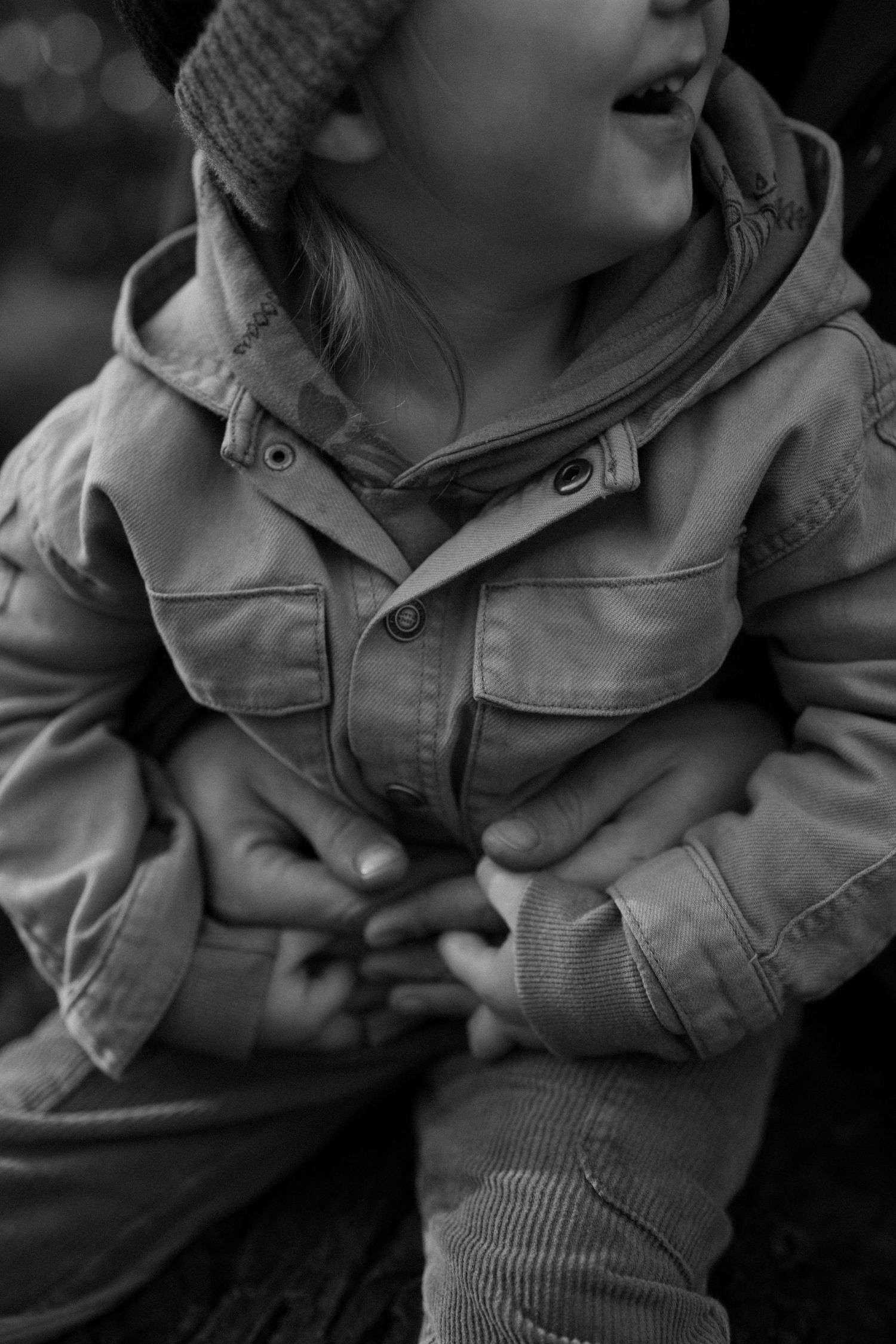 Close-up black and white photo of child wearing winter coat and knit beanie.