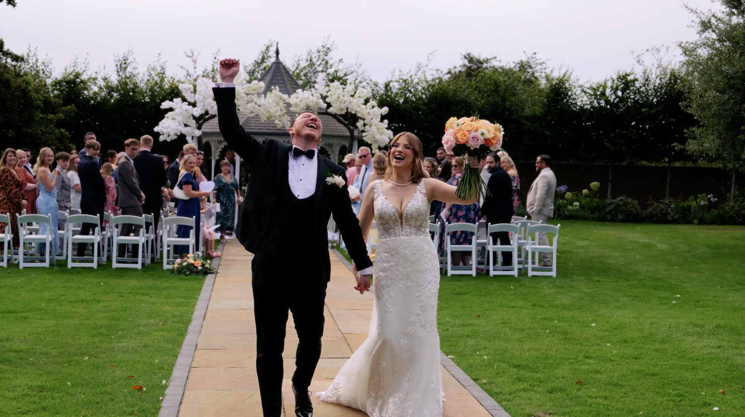 Outdoor wedding celebration with white chairs set up on a green lawn at dusk. Vaulty Manor, Maldon.