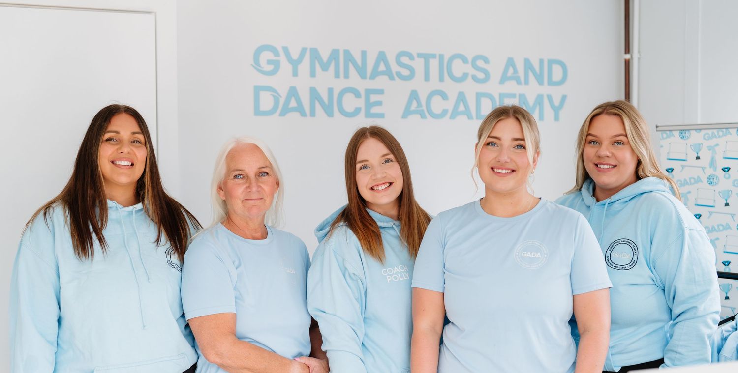 Staff members in light blue shirts standing together at a gymnastics and dance academy. Manningtree, Essex.