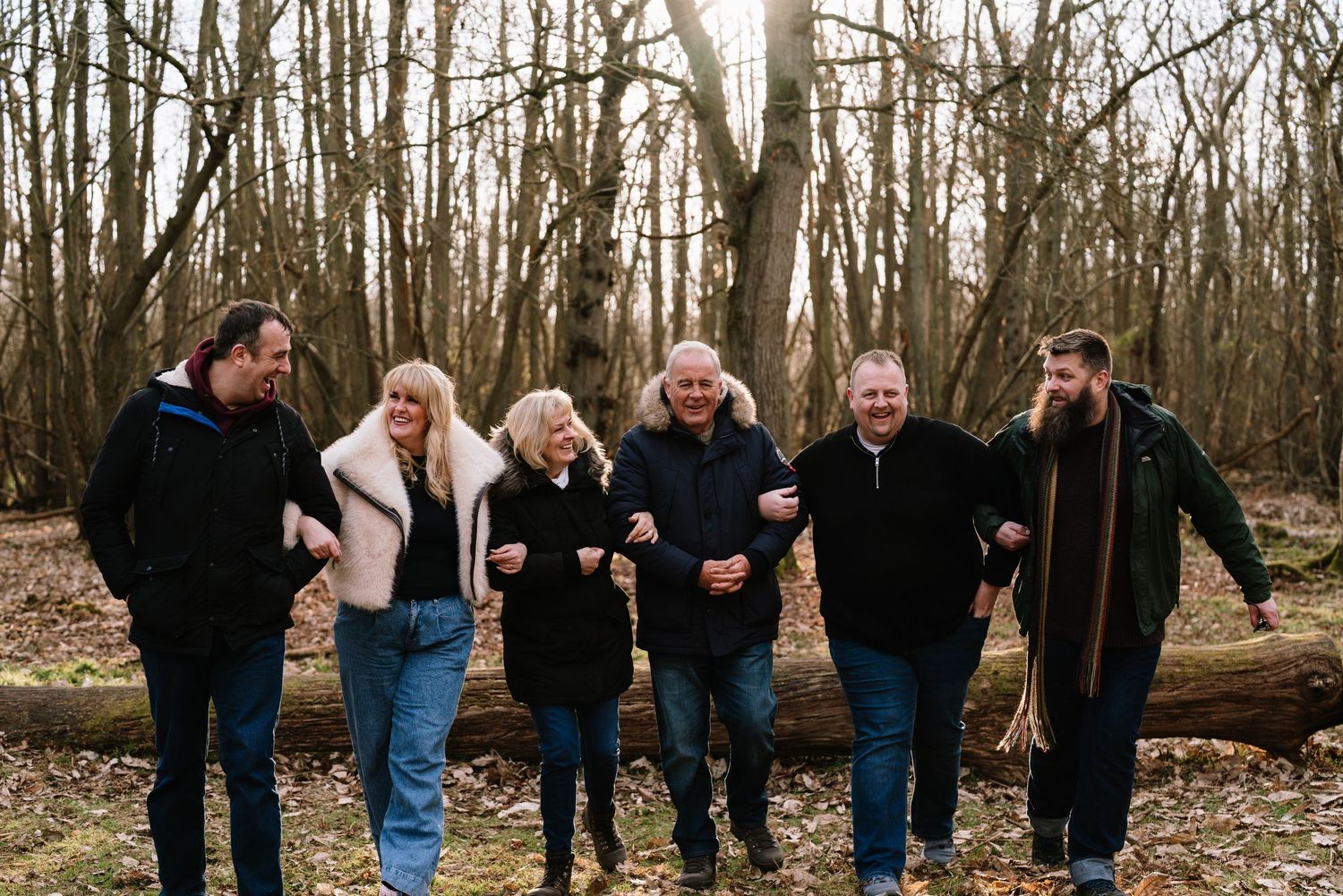 Group photo session with multiple people walking and posing in a winter forest landscape. Wrabness Woods, Essex.