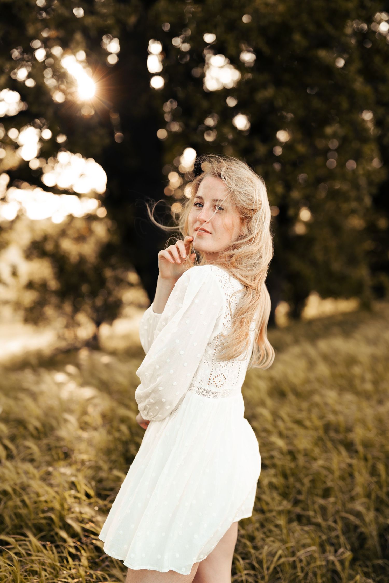Whimsical outdoor photography in a field with bokeh lighting and a white lace dress. Manningtree, Essex.
