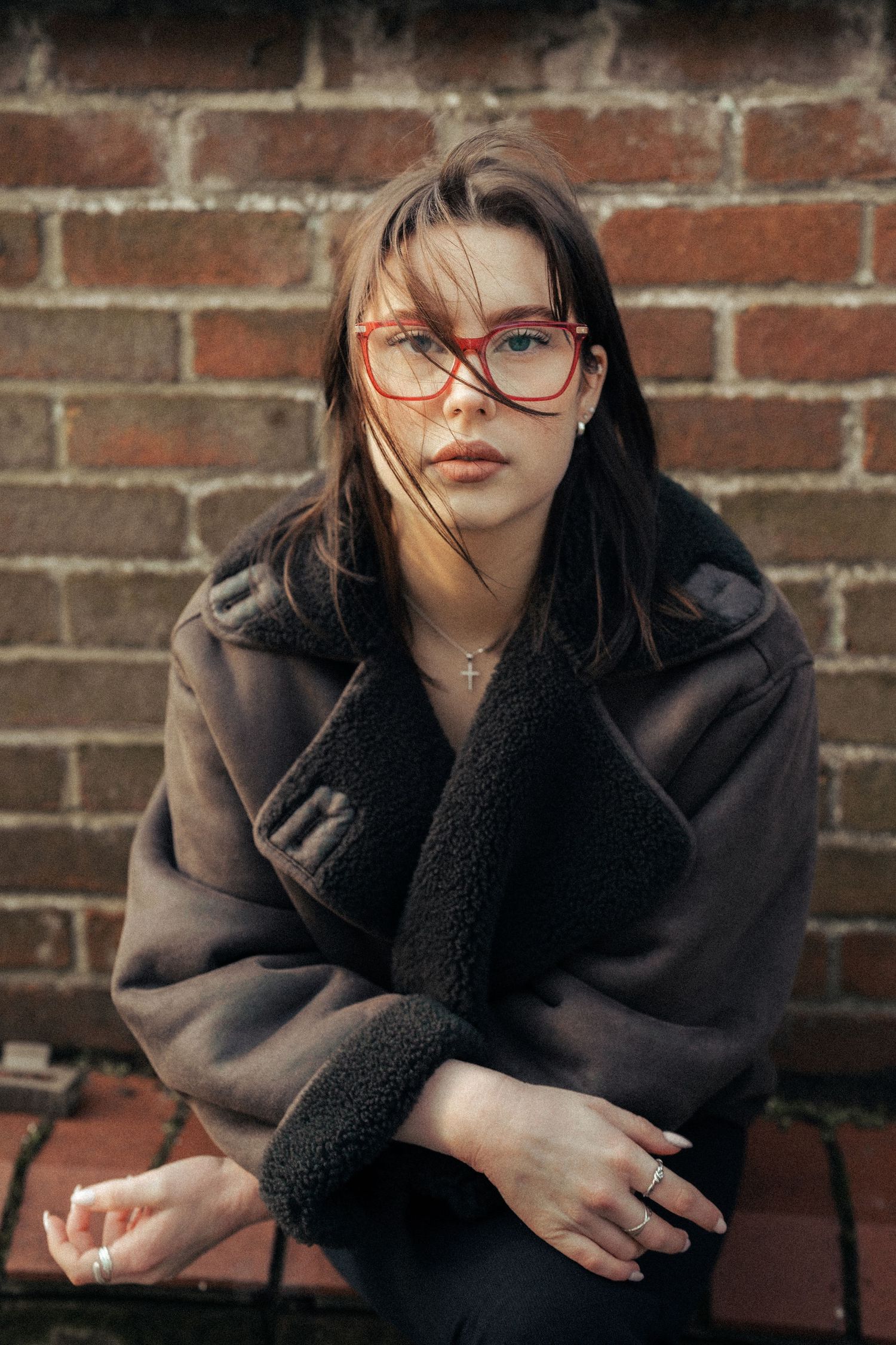 Cozy winter fashion portrait with black sherpa coat against brick background. Old Harwich, Essex.