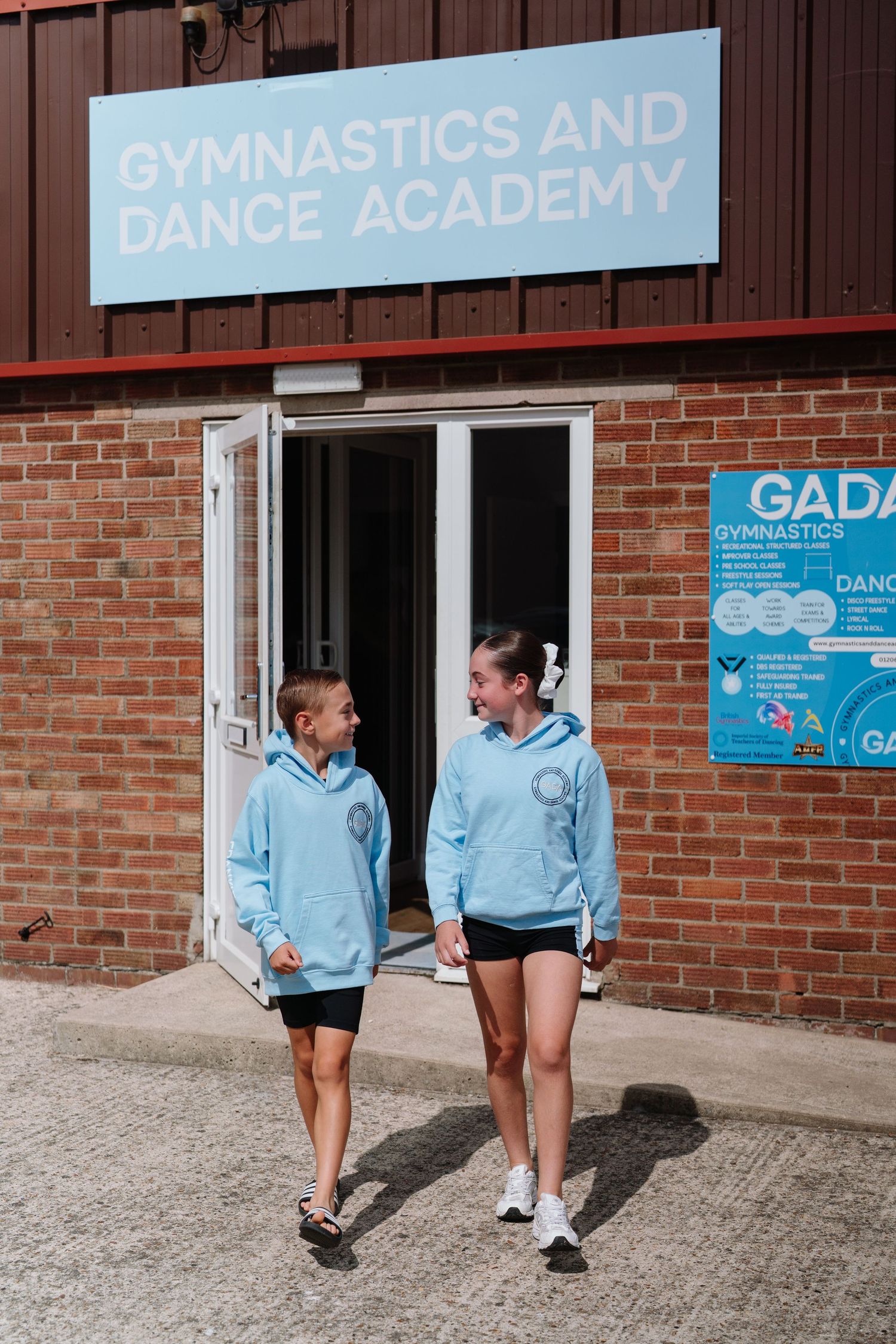 Students walking outside brick building with Gymnastics and Dance Academy signage. Manningtree, Essex.