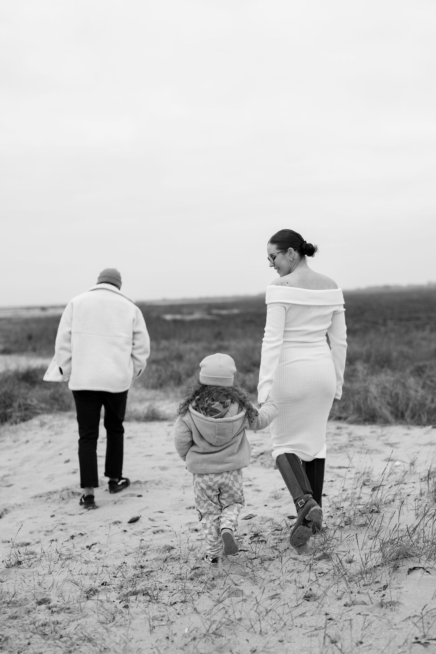 Family walking up sandy dune path in black and white. Earlhams Beach, Harwich, Essex.