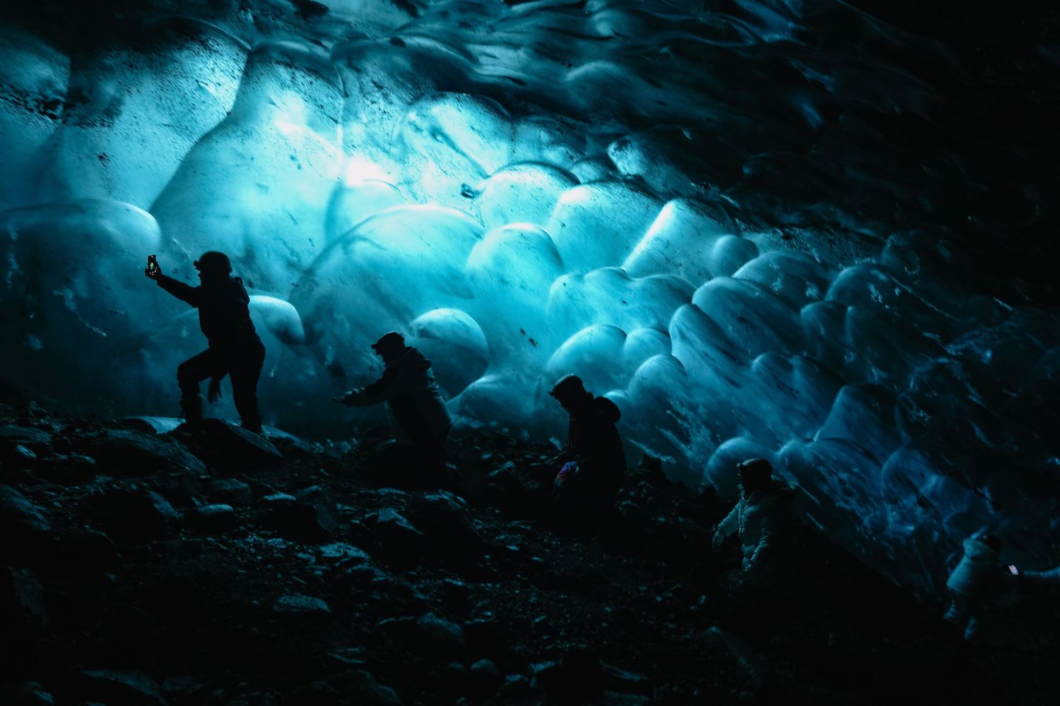 Stunning blue ice formations illuminate a natural glacier cave with dramatic lighting effects. Iceland.
