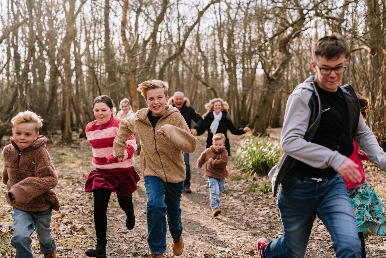 Playful sequence of people running and chasing through a wooded forest path. Wrabness Woods, Essex.