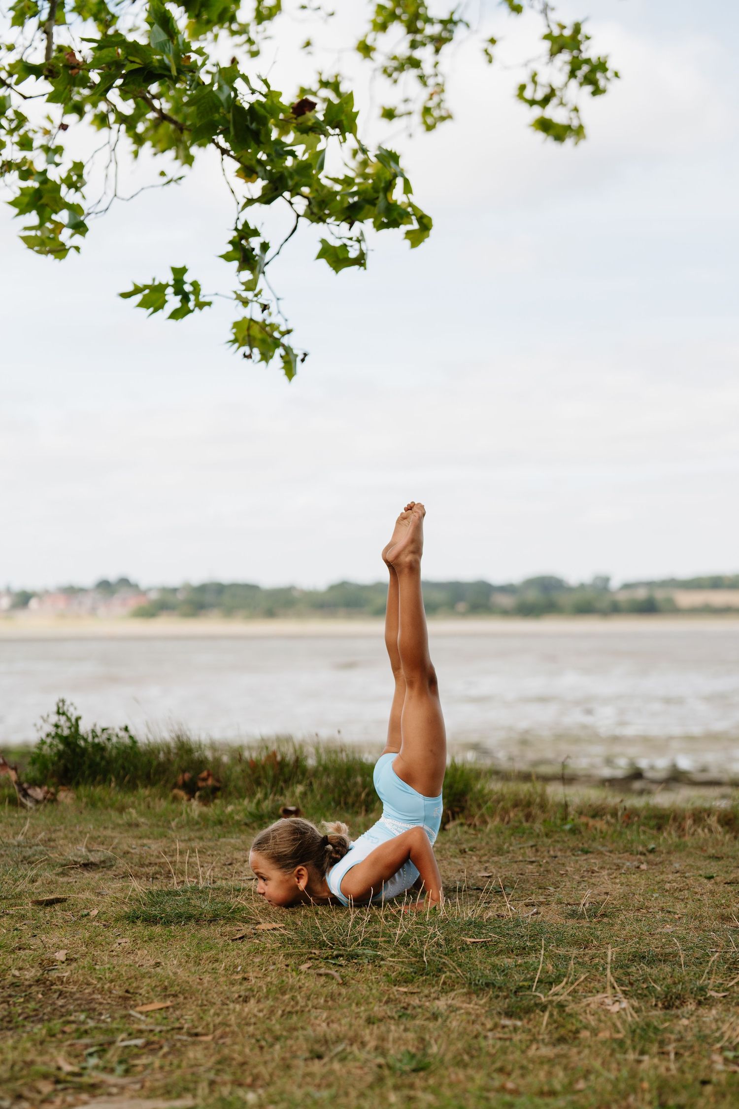 Gymnast practicing outdoor moves against scenic coastal background. Manningtree, Essex.