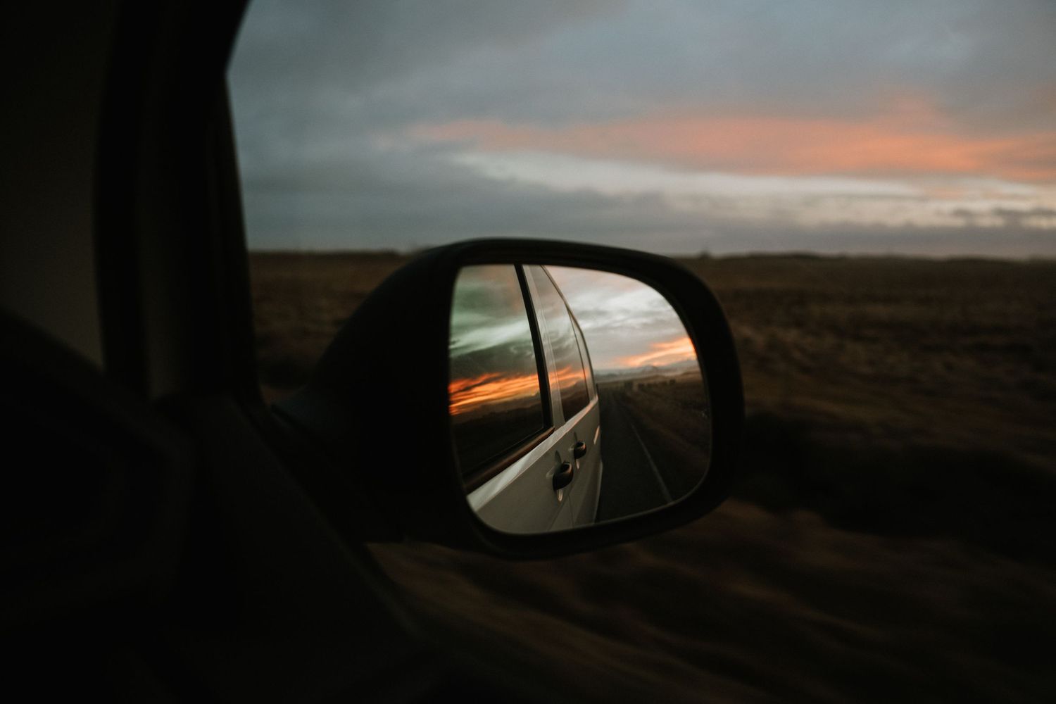 Scenic sunset view through a car window of an empty rural highway stretching into the distance. Iceland.