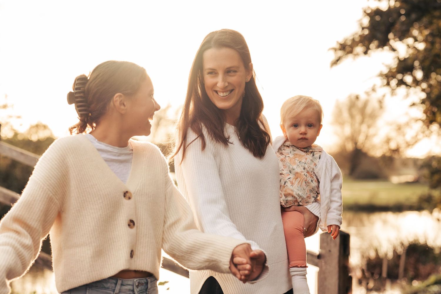 Family members in cream-colored sweaters share joyful moments during golden hour. Flatford Mill.