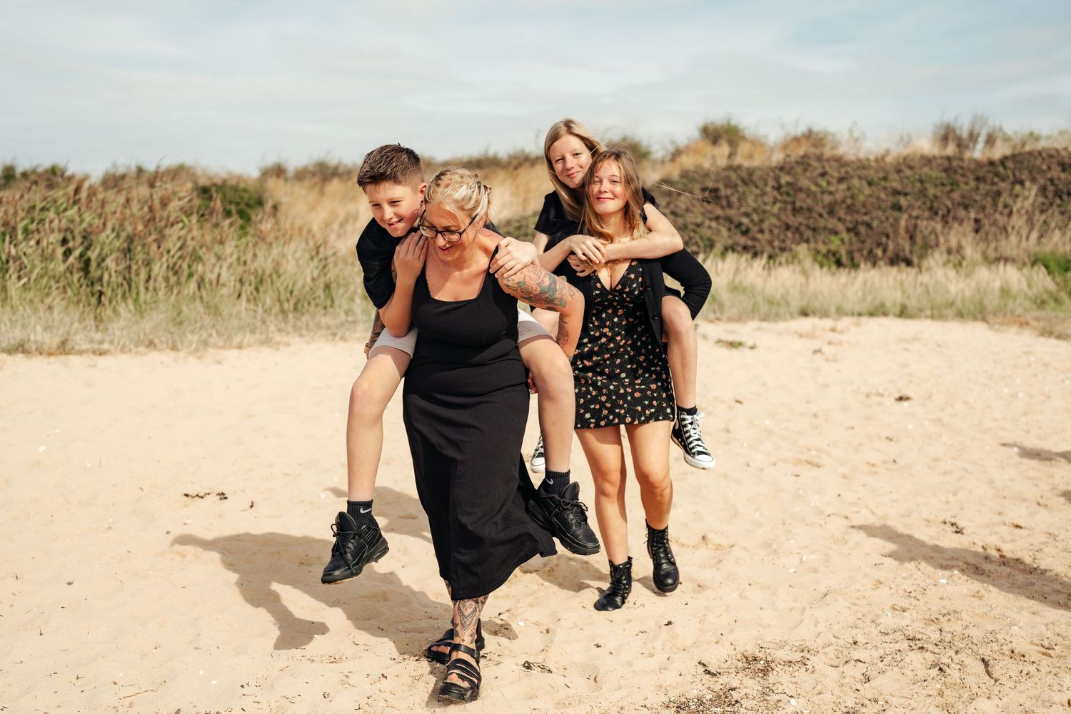 Family members play and laugh together on a sandy beach during a photo session. Earlhams Beach, Harwich, Essex.