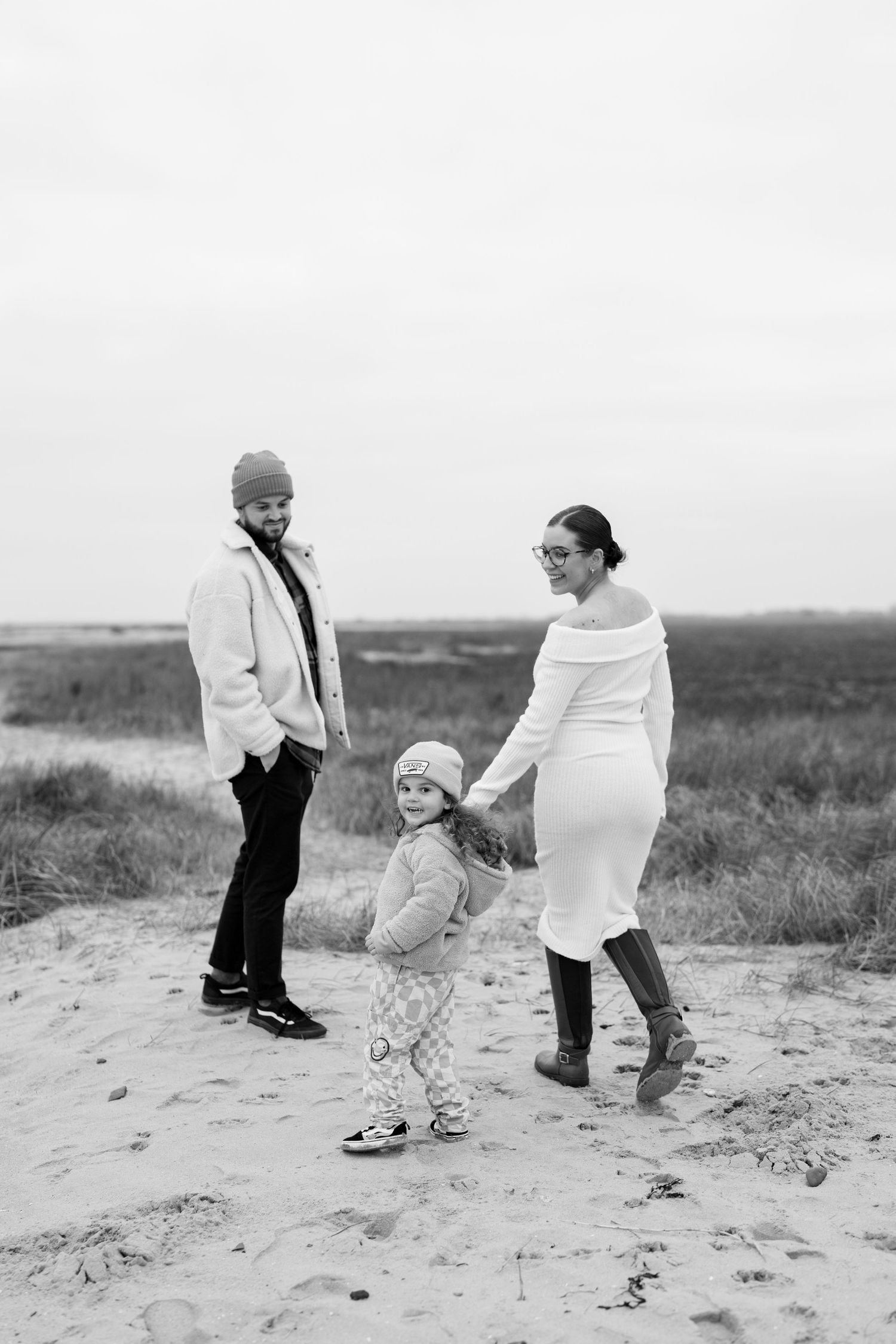 Playful couple walking and posing together on sandy beach terrain. Earlhams Beach, Harwich, Essex.