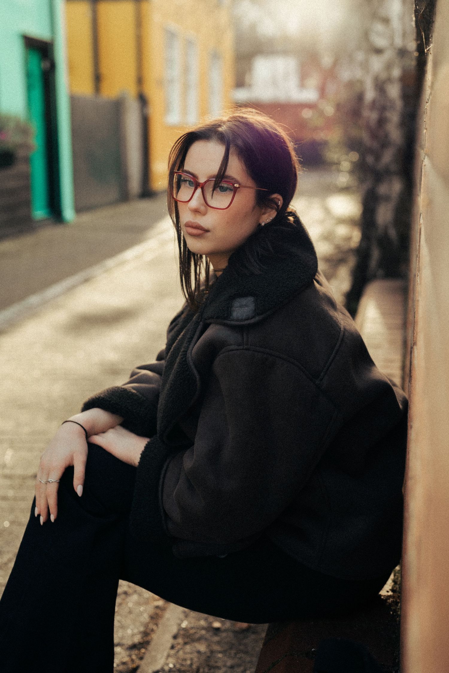 Artistic outdoor portrait against colorful wall wearing dark winter coat. Old Harwich, Essex.