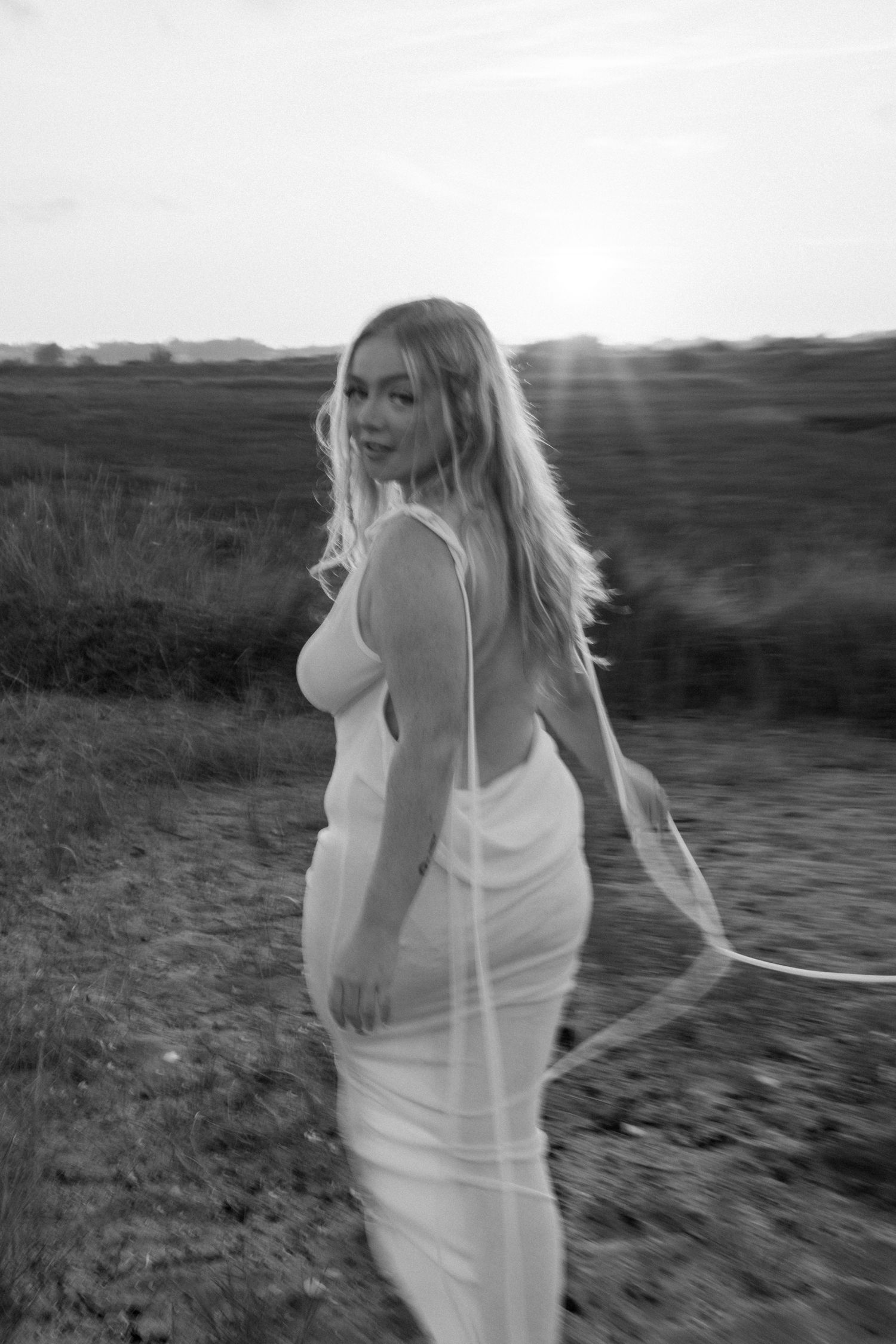 Black and white series of a person dancing freely in a flowing white dress outdoors. Earlhams Beach, Harwich, Essex.