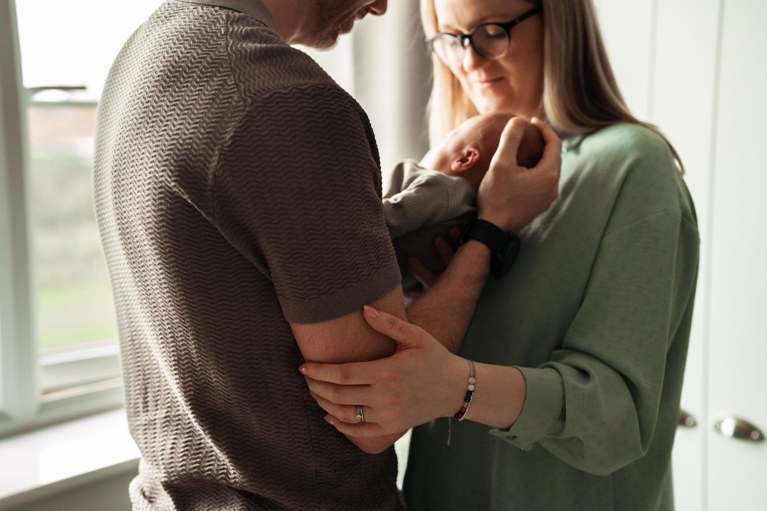 Intimate couple embraces in cozy indoor setting wearing casual sweaters.