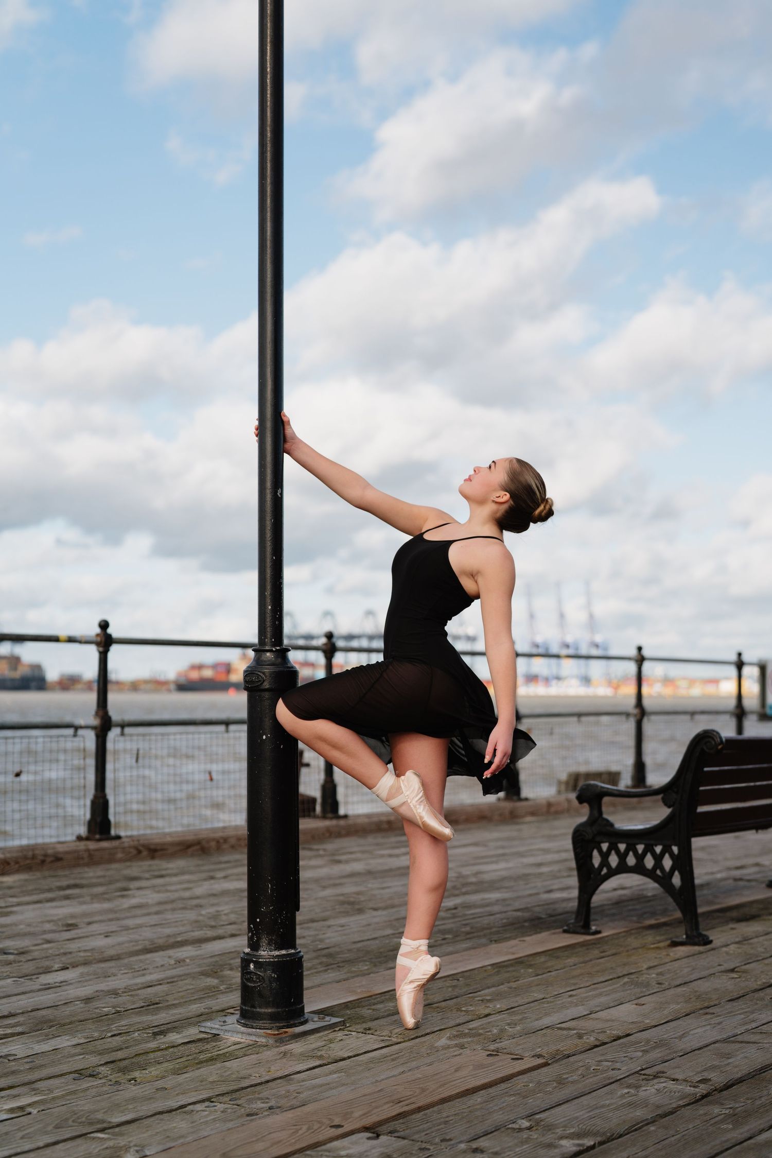 Ballet dancer performs graceful poses on waterfront boardwalk with industrial port background. Old Harwich, Essex.