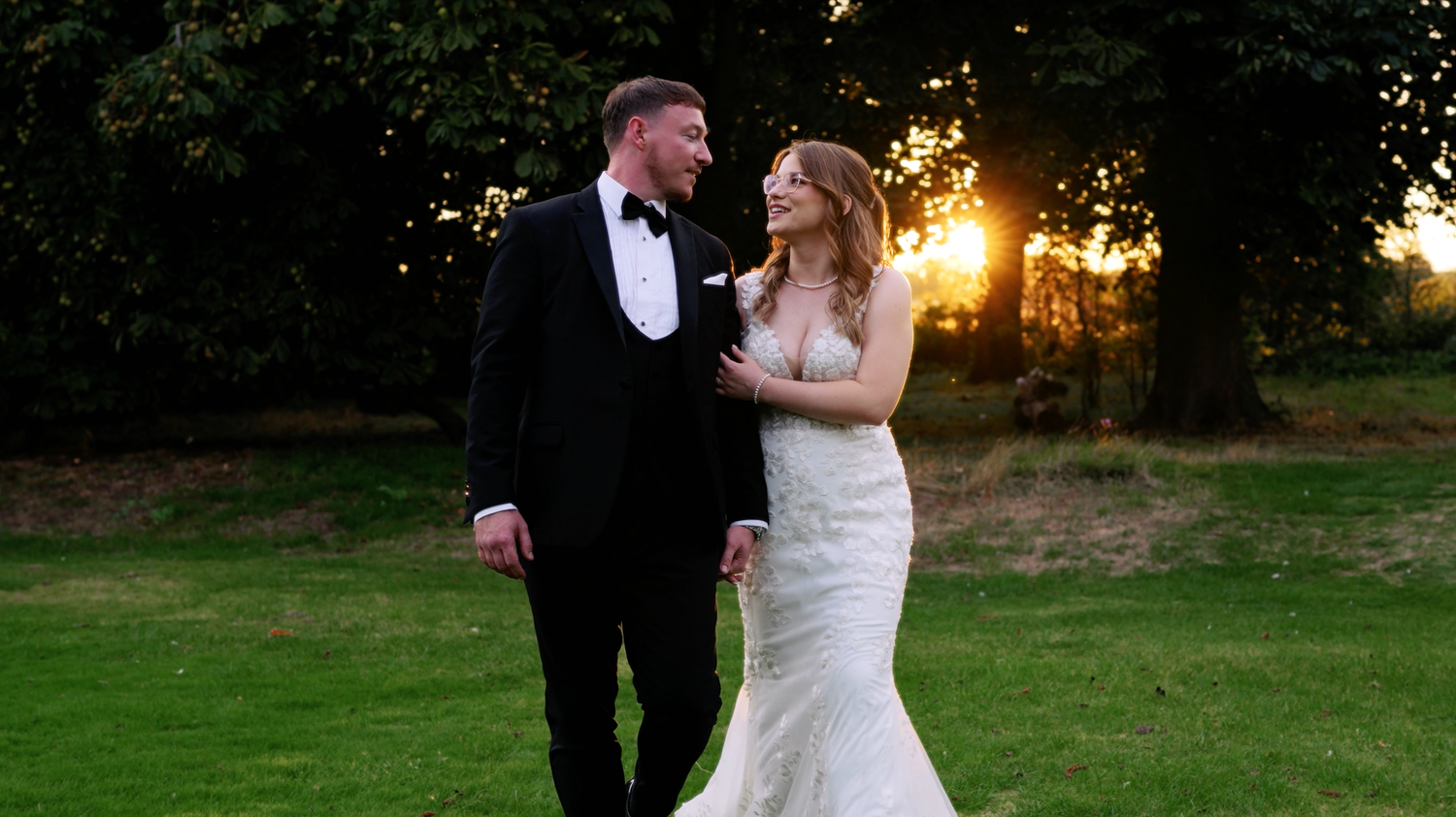 Couple walking together on their wedding day with the dreamy golden light shining through the trees behind them. Vaulty Manor, Maldon.
