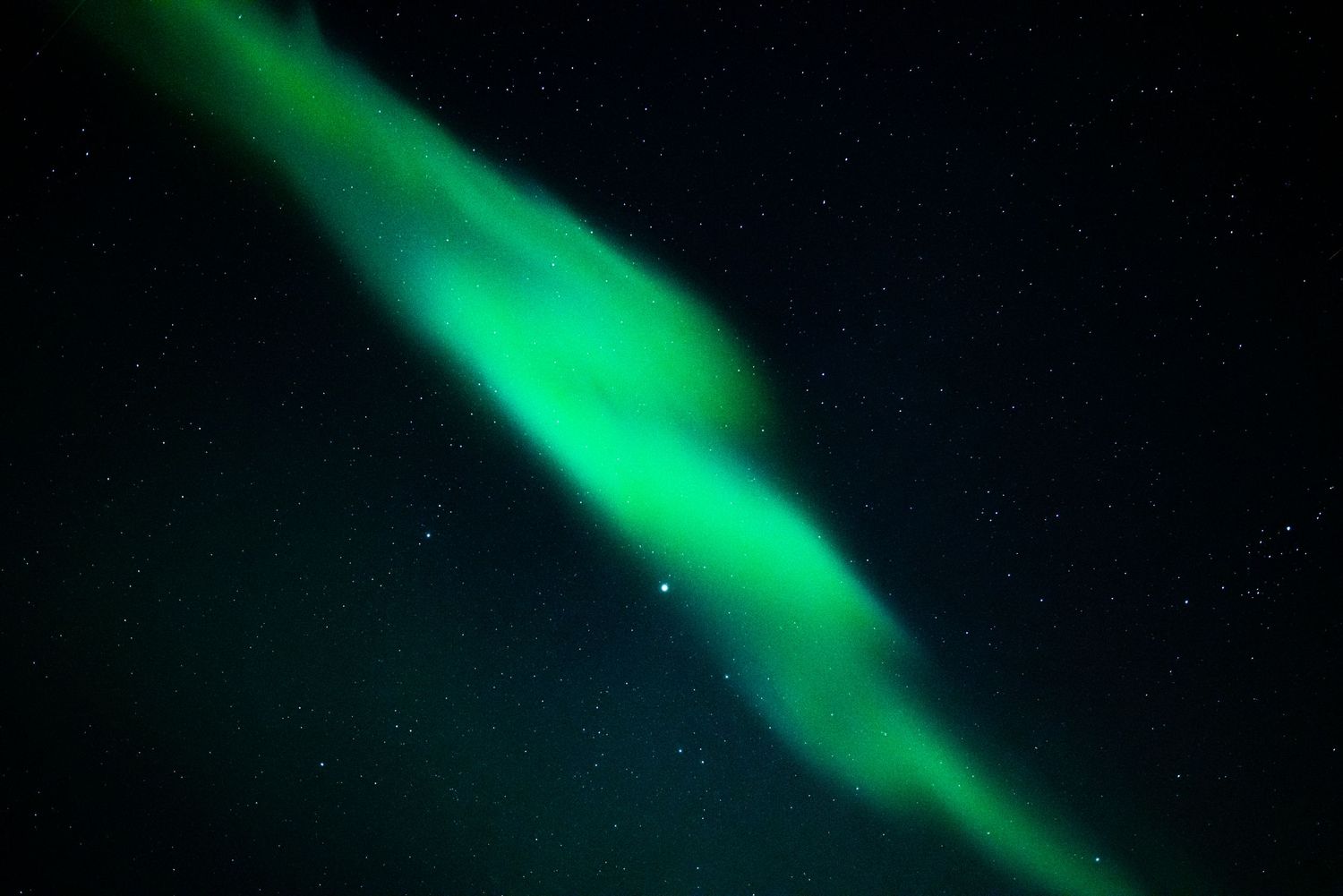 Swirling emerald northern lights illuminate the night sky with ethereal green ribbons. Norway.