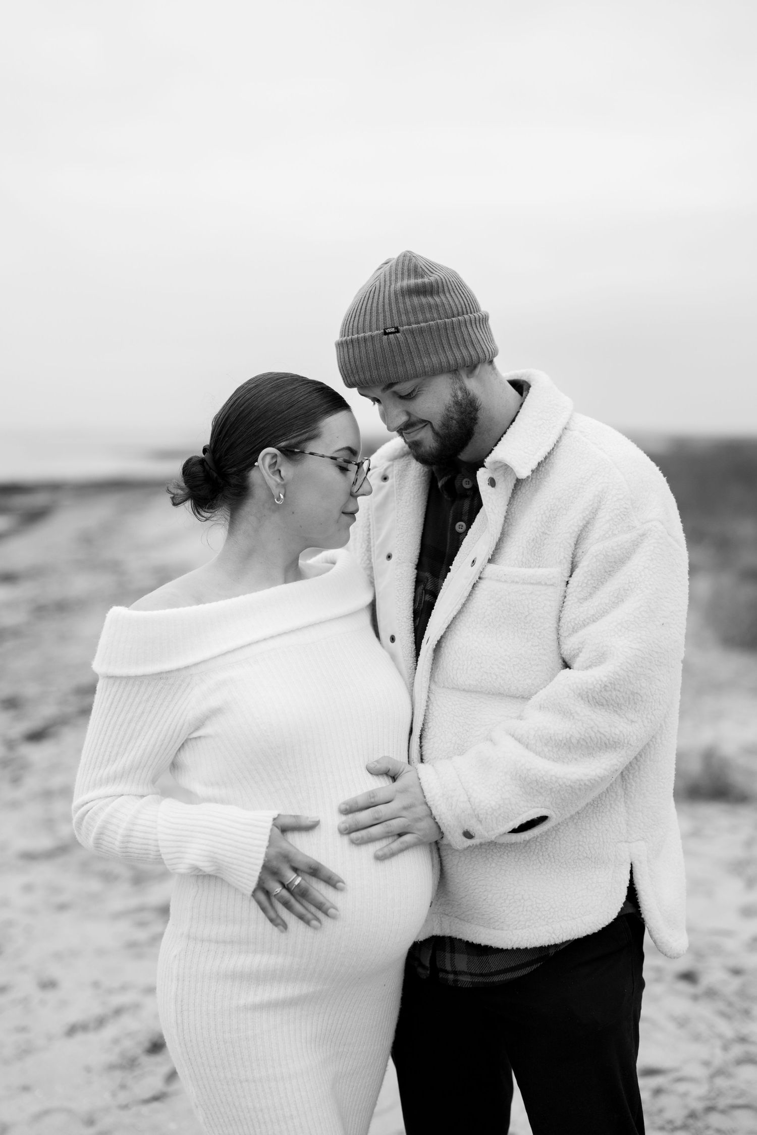 Romantic couple in winter wear sharing tender moments on cloudy beach. Earlhams Beach, Harwich, Essex.