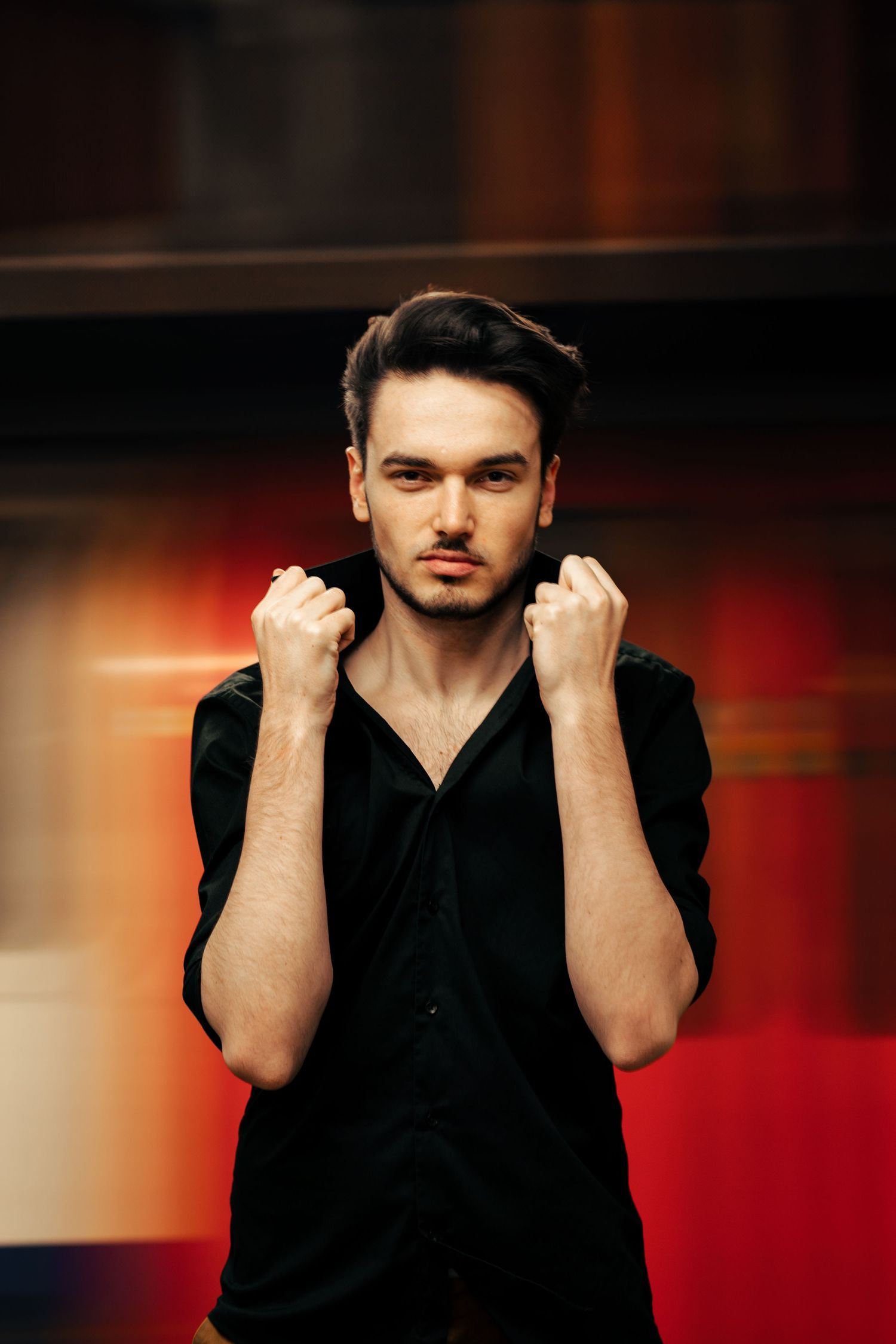 Portrait against red background showing dramatic lighting and black clothing. London, UK.