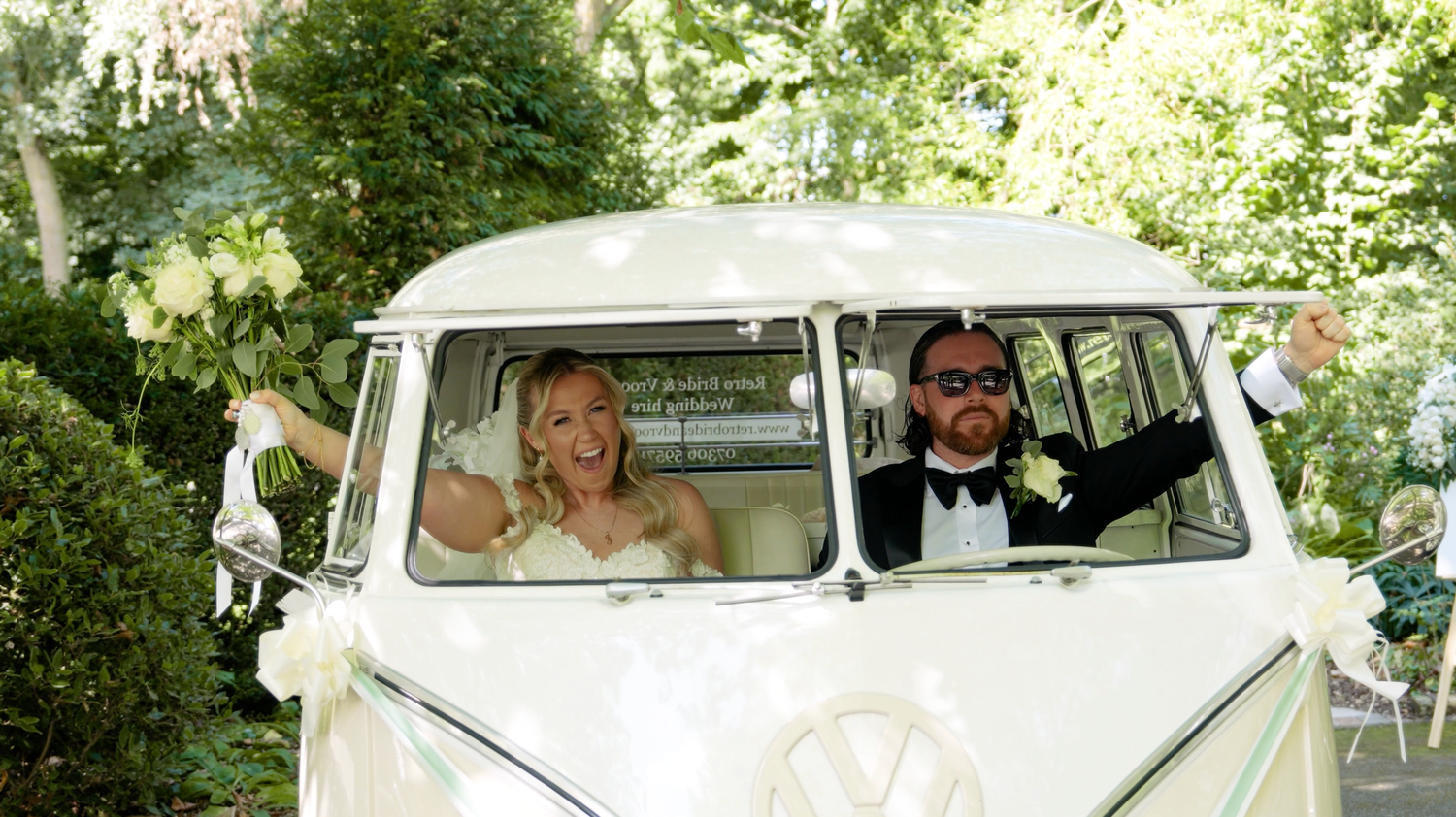 A white vintage Volkswagen van parked on a tree-lined path during a wedding. The Barn Brasserie.