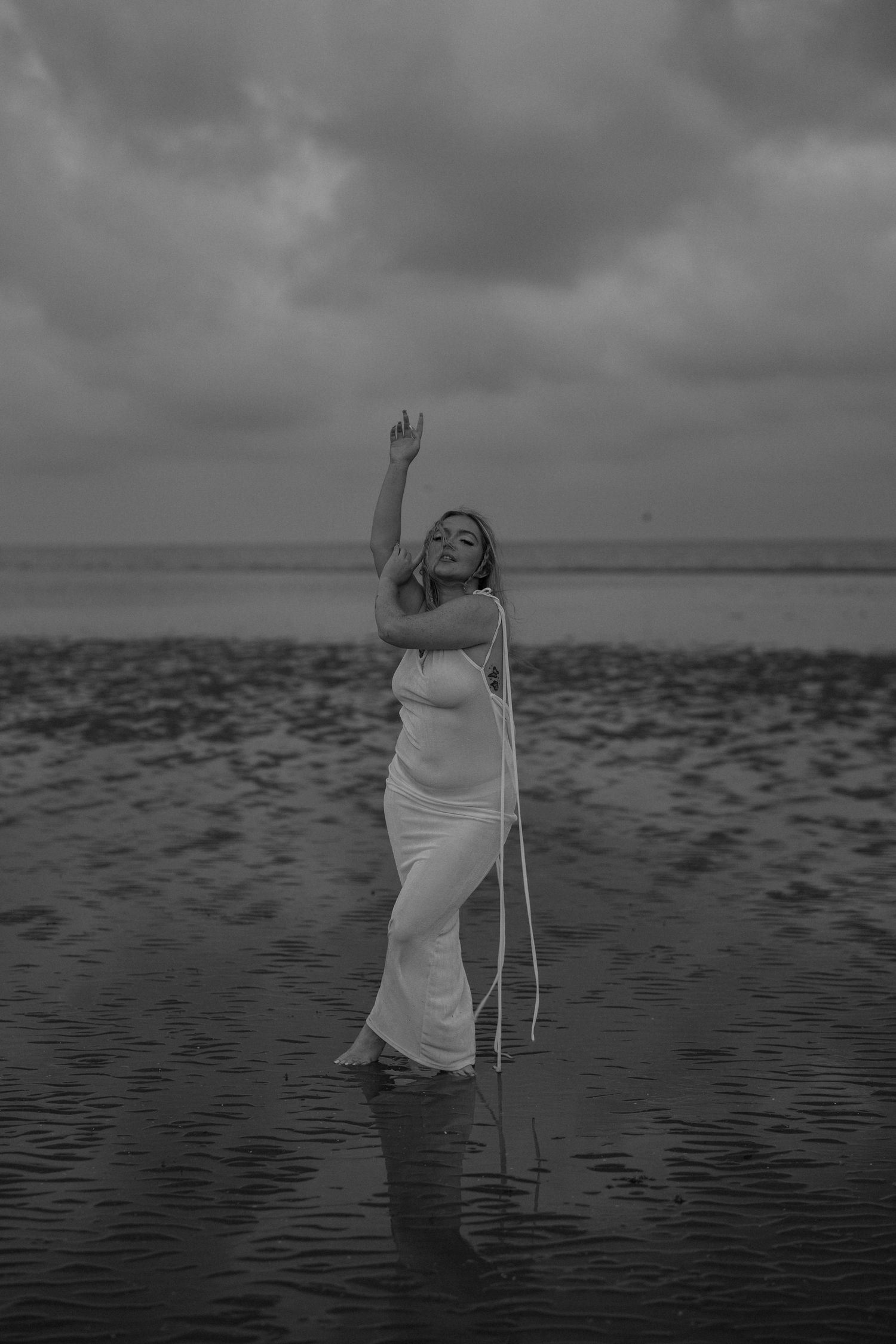 Artistic black and white photo of someone in a flowing dress standing in shallow water. Earlhams Beach, Harwich, Essex.