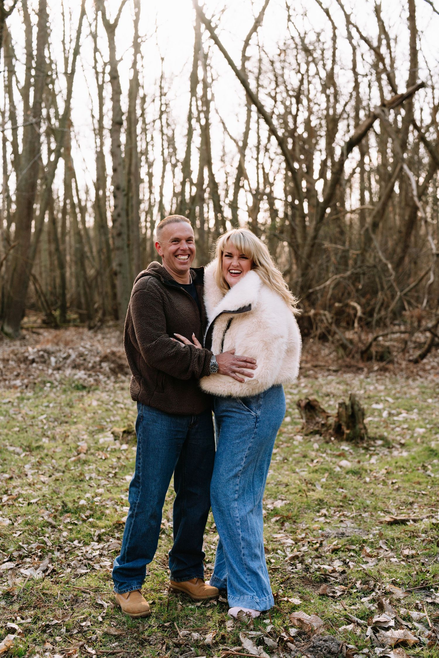 Candid couple photos in a forest setting with bare winter trees in the background. Wrabness Woods, Essex.
