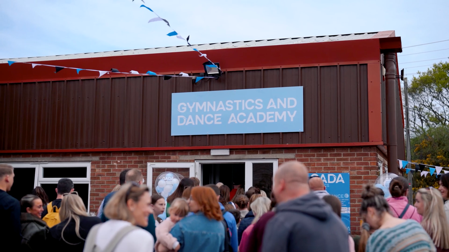 Red exterior of dance academy building with signage and blue sky. Manningtree, Essex.