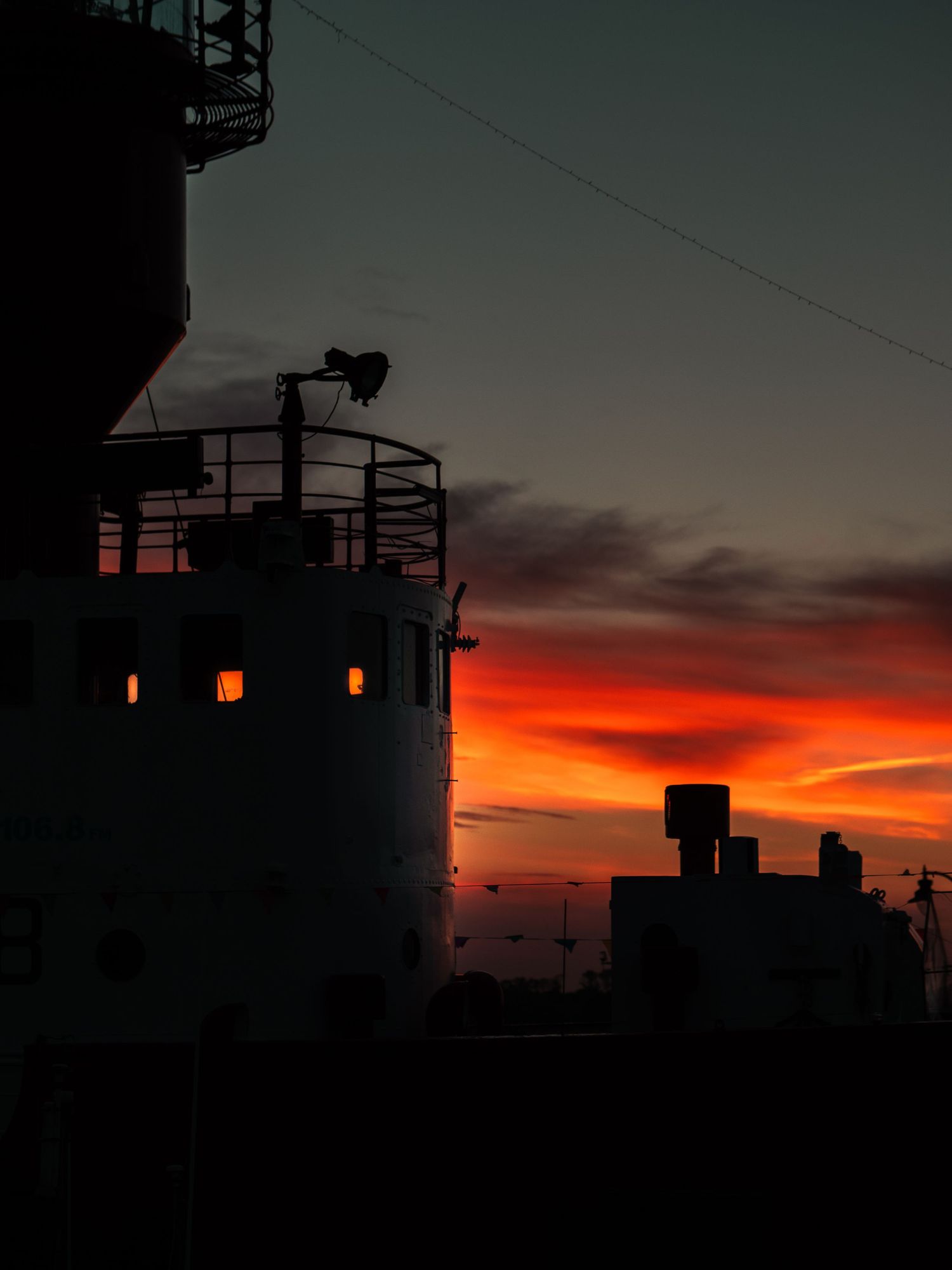Industrial building silhouette against dramatic red sunset sky with glowing windows. Old Harwich, Essex.