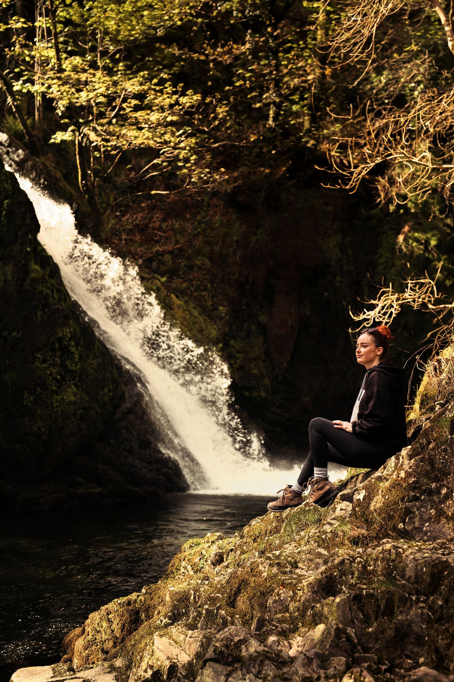 A peaceful moment by a cascading waterfall with mossy rocks and autumn foliage. Wales.